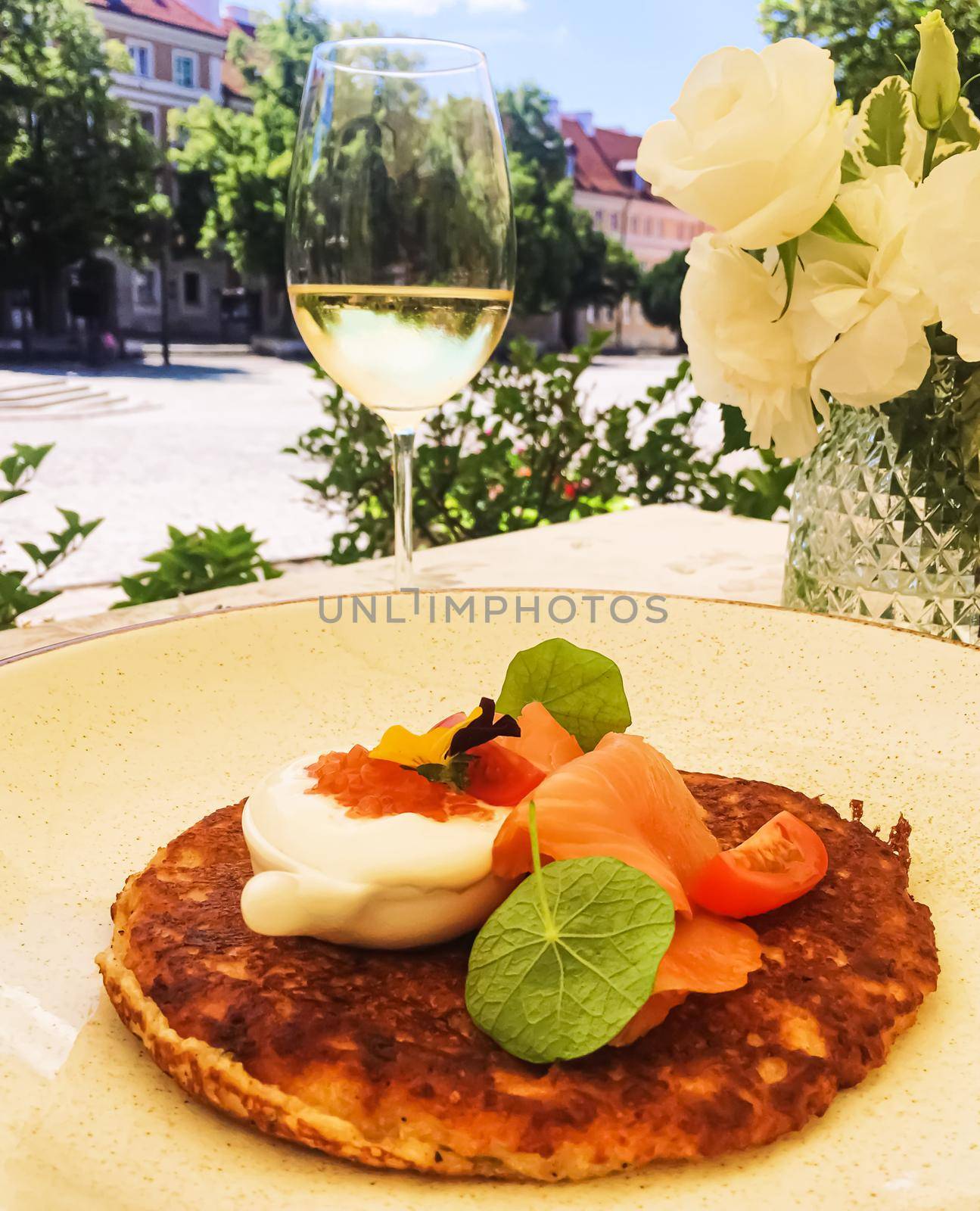 Potato fritter pancake with red caviar, salmon and sour cream in luxury restaurant outdoors in summer by Anneleven