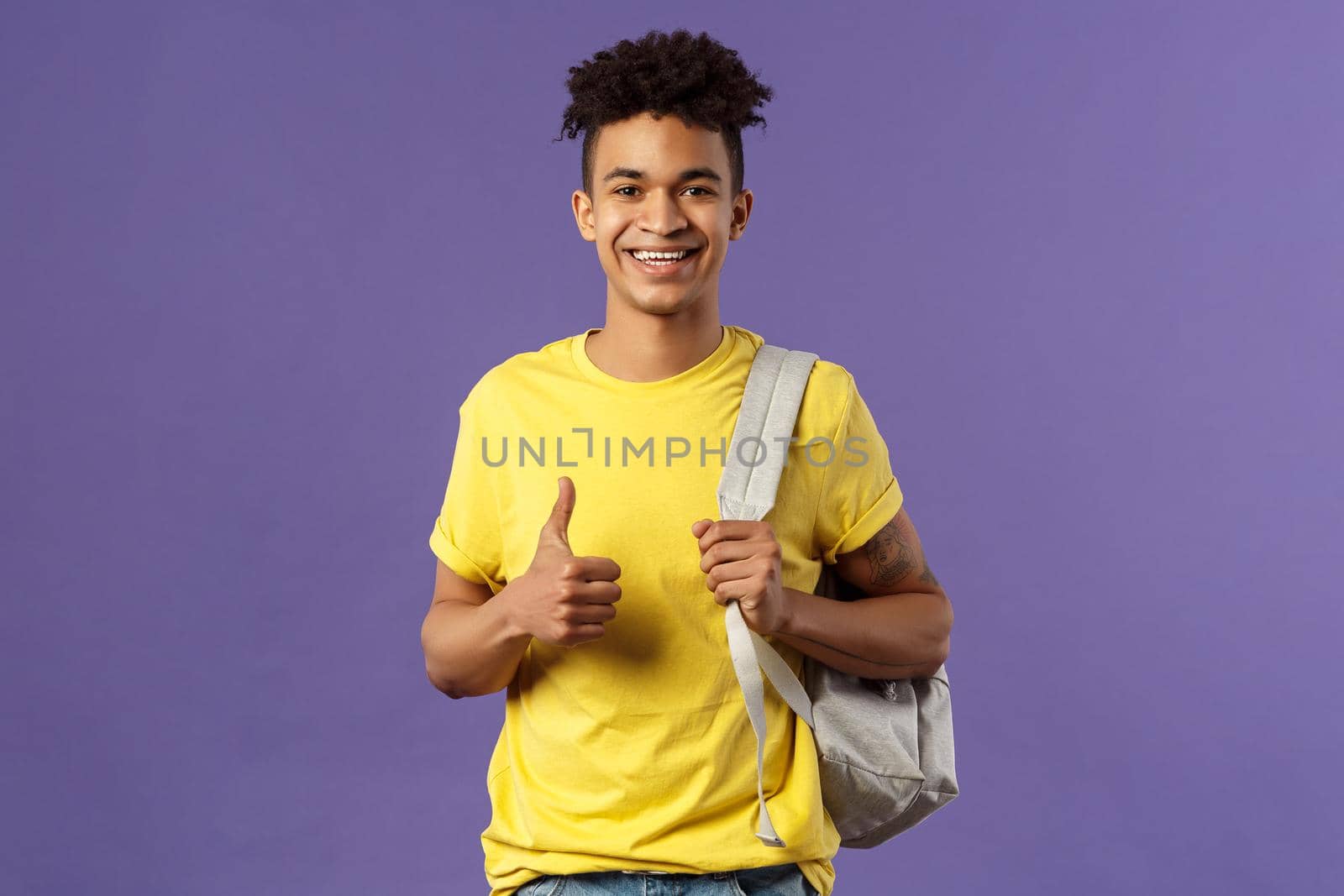 Back to school, university concept. Portrait of cheerful handsome male student describe his summer vacation to classmates, show recommendation, thumbs-up approval, hold backpack by Benzoix