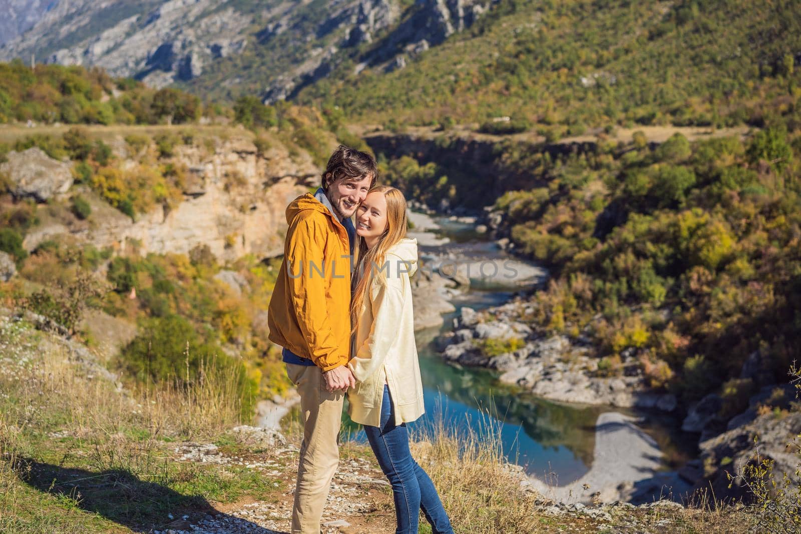 Montenegro. Happy couple man and woman tourists on the background of Clean clear turquoise water of river Moraca in green moraca canyon nature landscape. Travel around Montenegro concept.