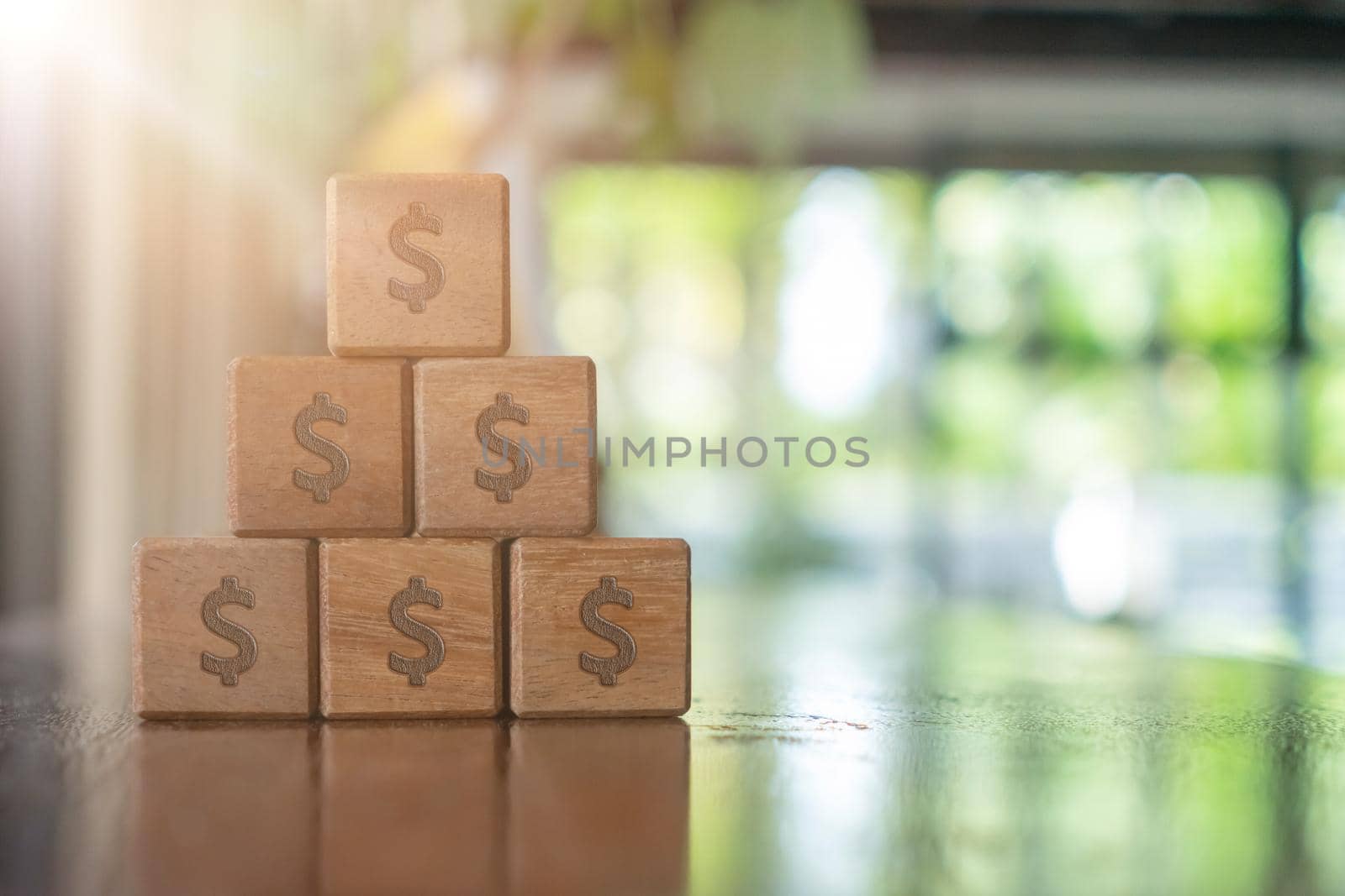 A set of wooden cubes on a table with a dollar symbol on the background as a metaphor for money or wealth saving. by Suwant