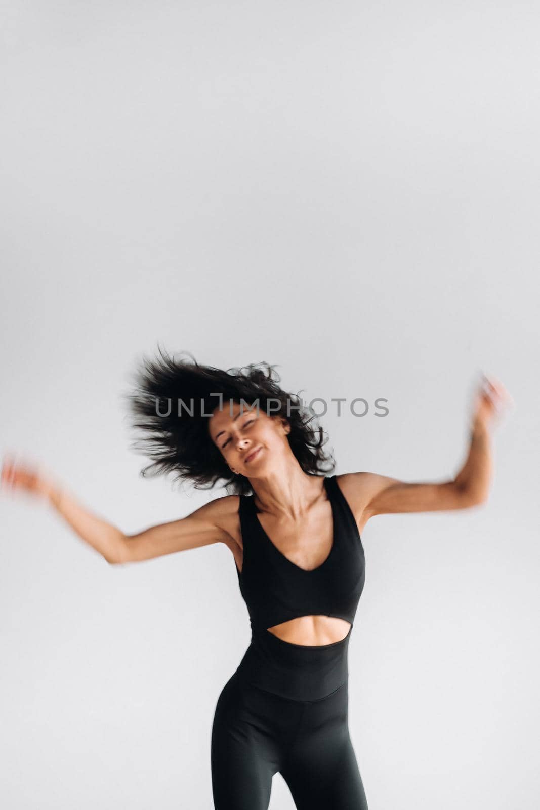 A blurry silhouette of a woman in black sportswear is engaged in dynamic kali meditation in the yoga hall.