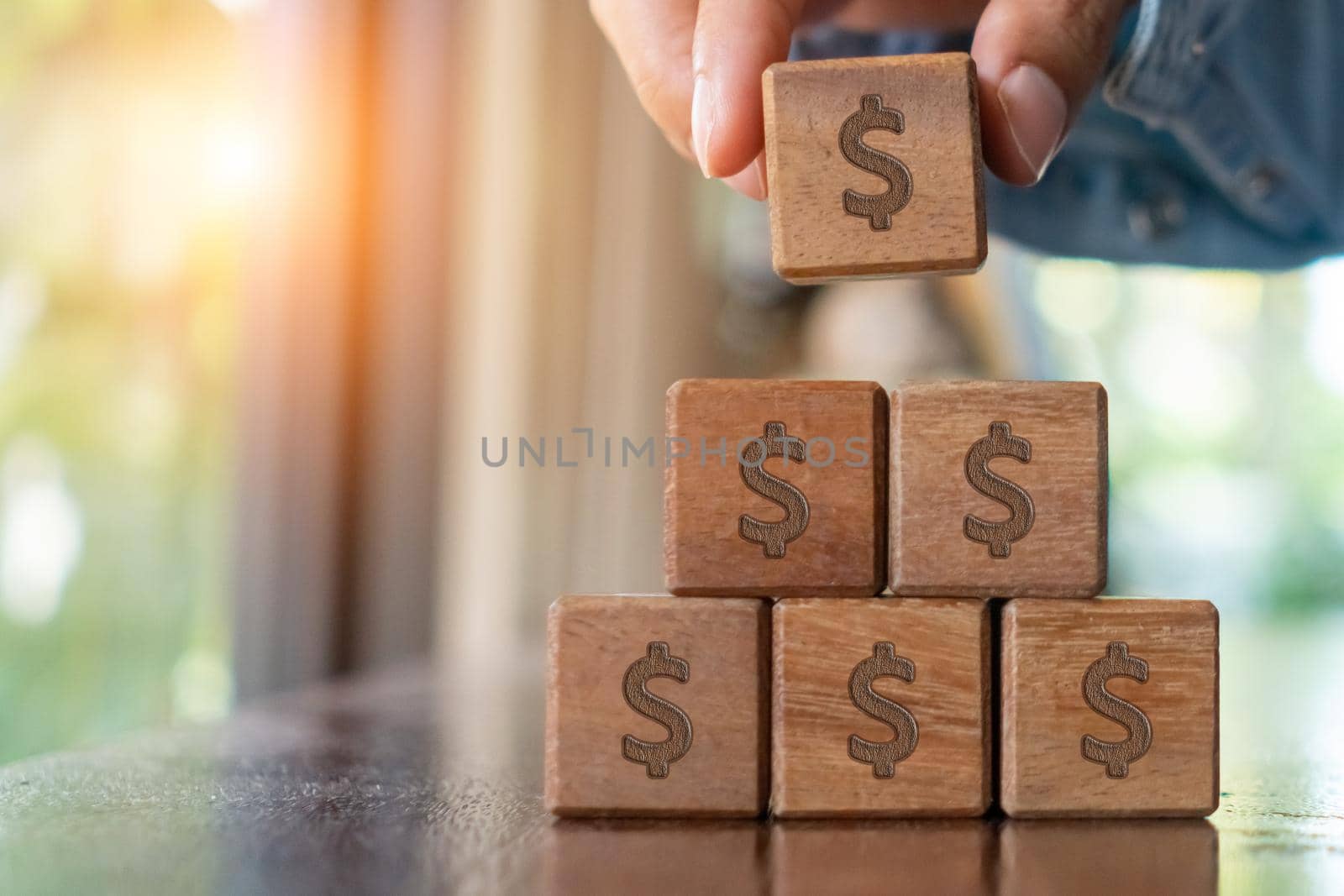 A set of wooden cubes on a table with a dollar symbol on the background as a metaphor for money or wealth saving. by Suwant