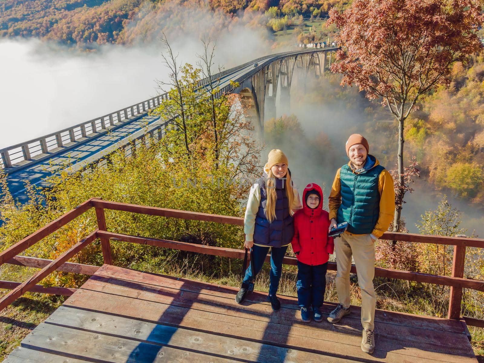 Montenegro. Happy family on the background of Dzhurdzhevich Bridge Over The River Tara foggy morning.