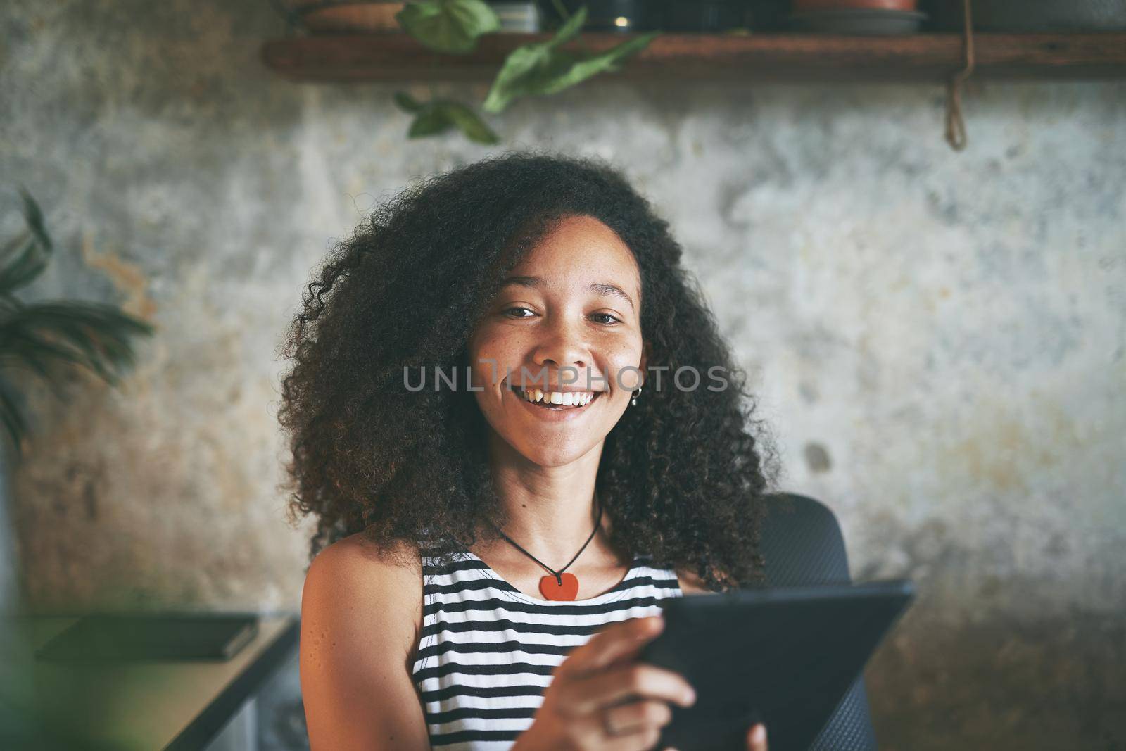 Shot of an attractive young african woman sitting alone and using her tablet while working from home stock photo