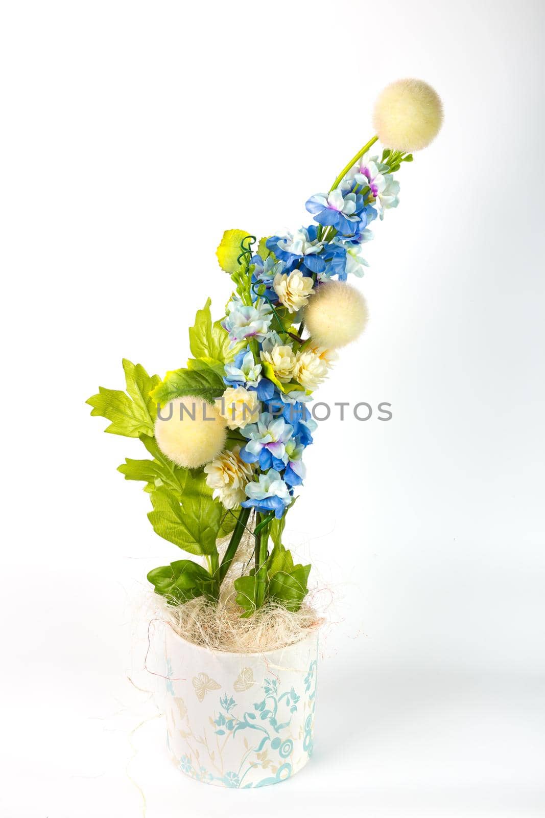 Composition with artificial flowers in a pot on white background. Ekibana from white and blue artificial flowers and green leaves.