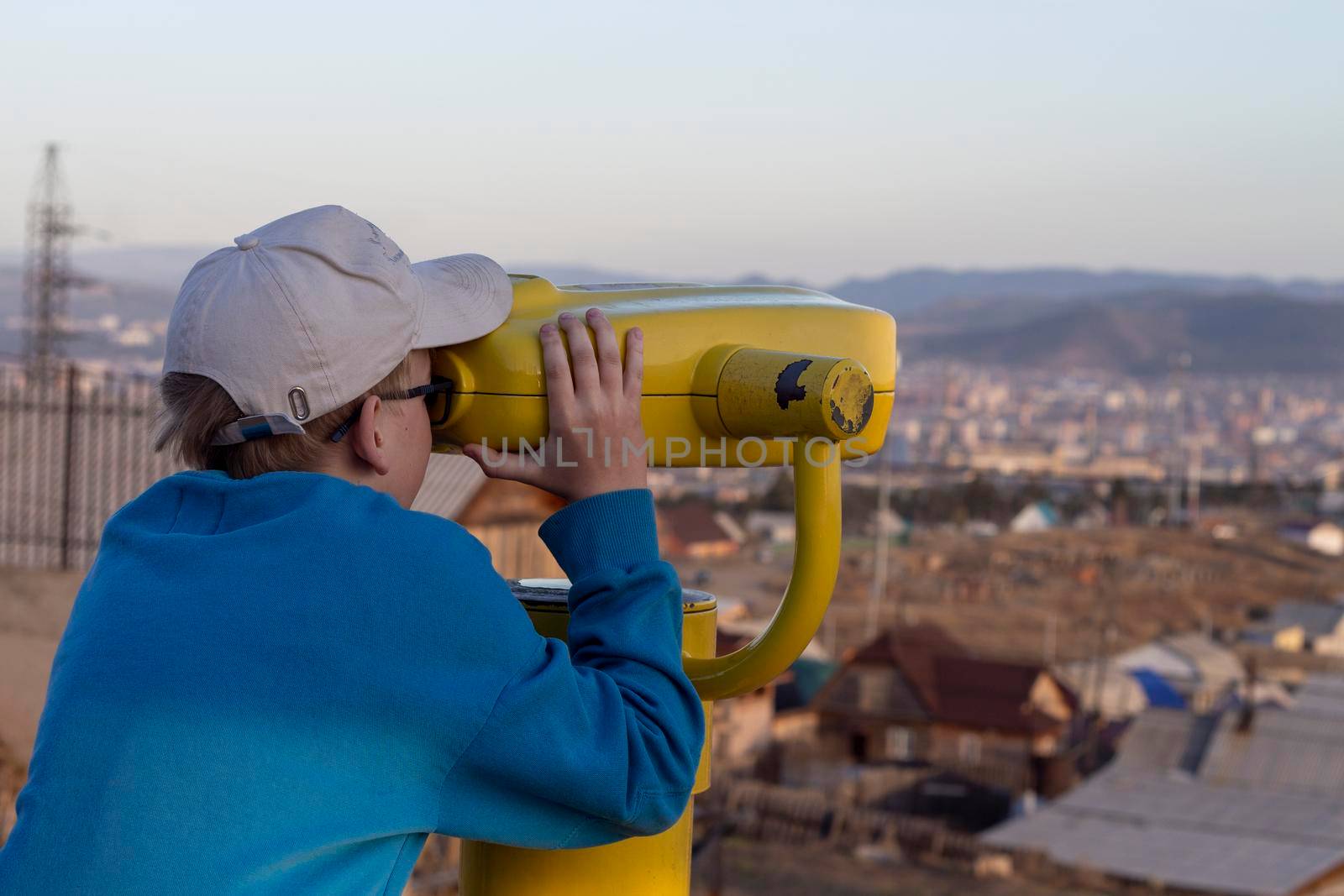 Boy looking through binocular at the city on the pointview