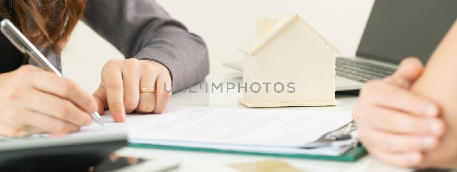 Client signs document regarding real estate activity next to lawyer or real estate agent sitting at office desk. Business concept of selling and buying house.