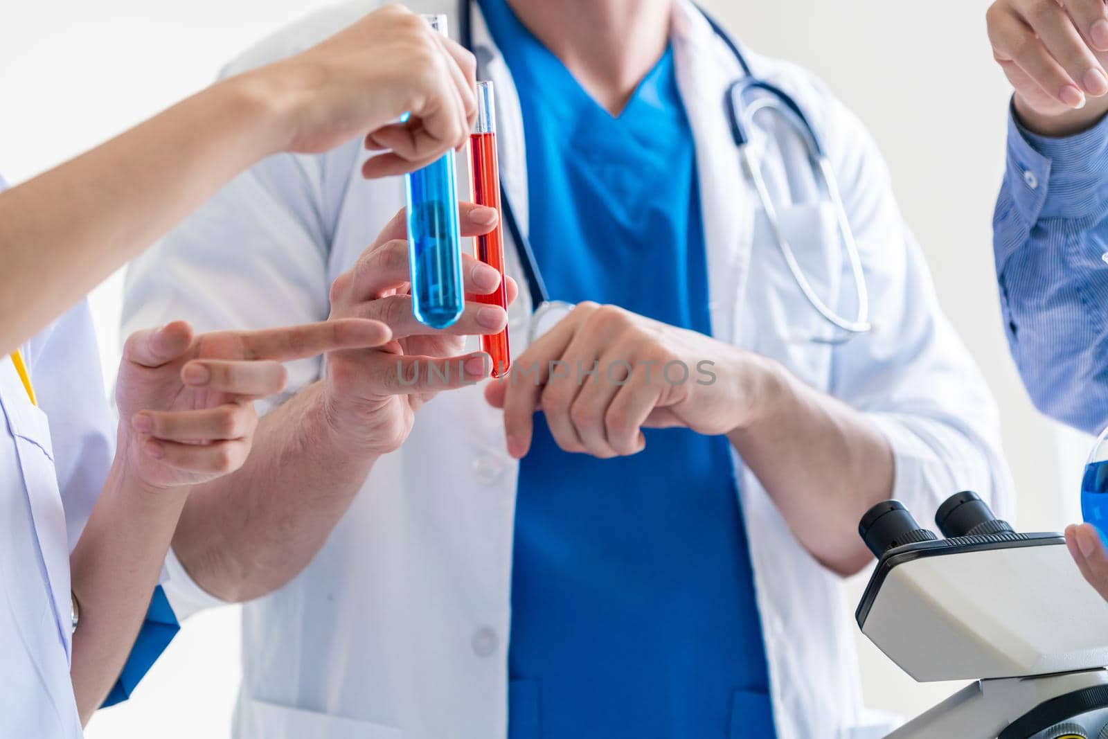 Group of scientists wearing lab coat working in laboratory while examining biochemistry sample in test tube and scientific instruments. Science technology research and development study concept.