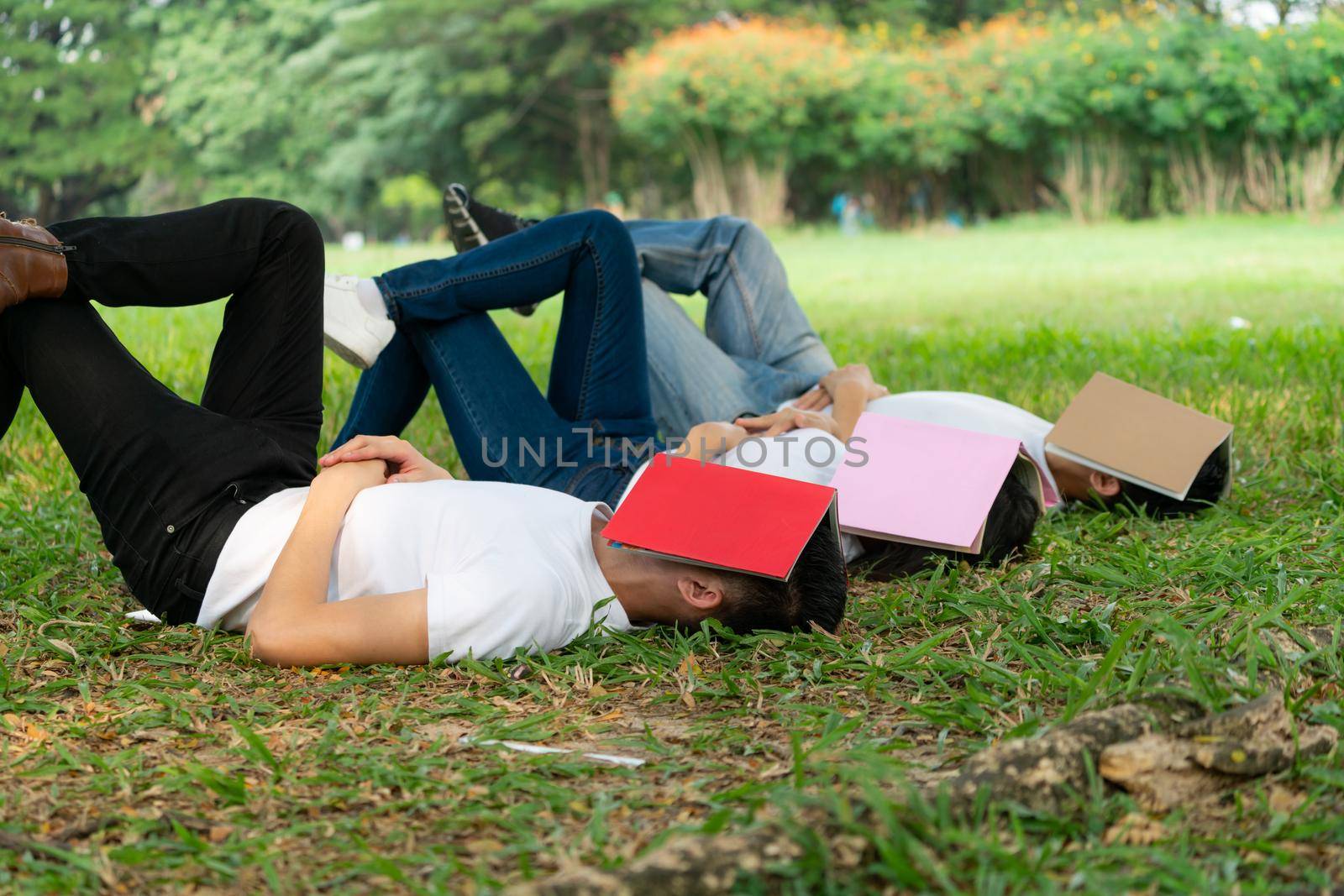 Funny students sleeping with books covering their face. Lazy and relaxation concept.