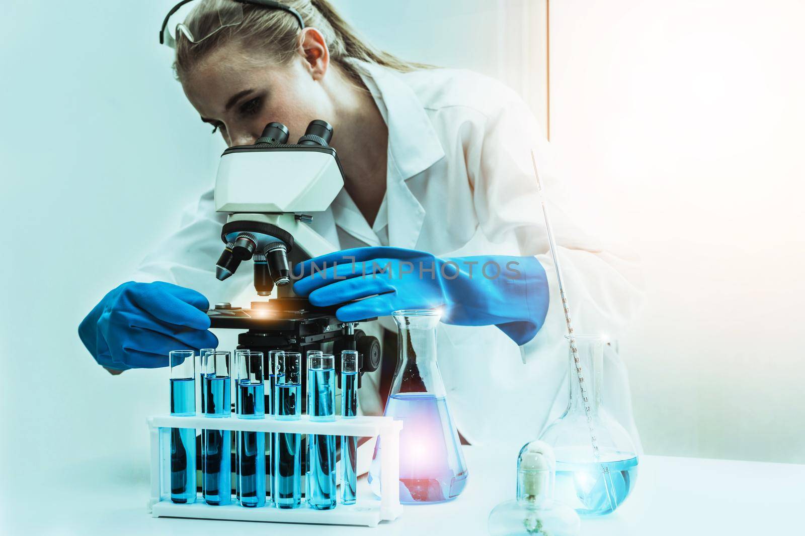 Young woman scientist working in chemical laboratory and examining biochemistry lab sample. Science technology medicine research and development study concept.