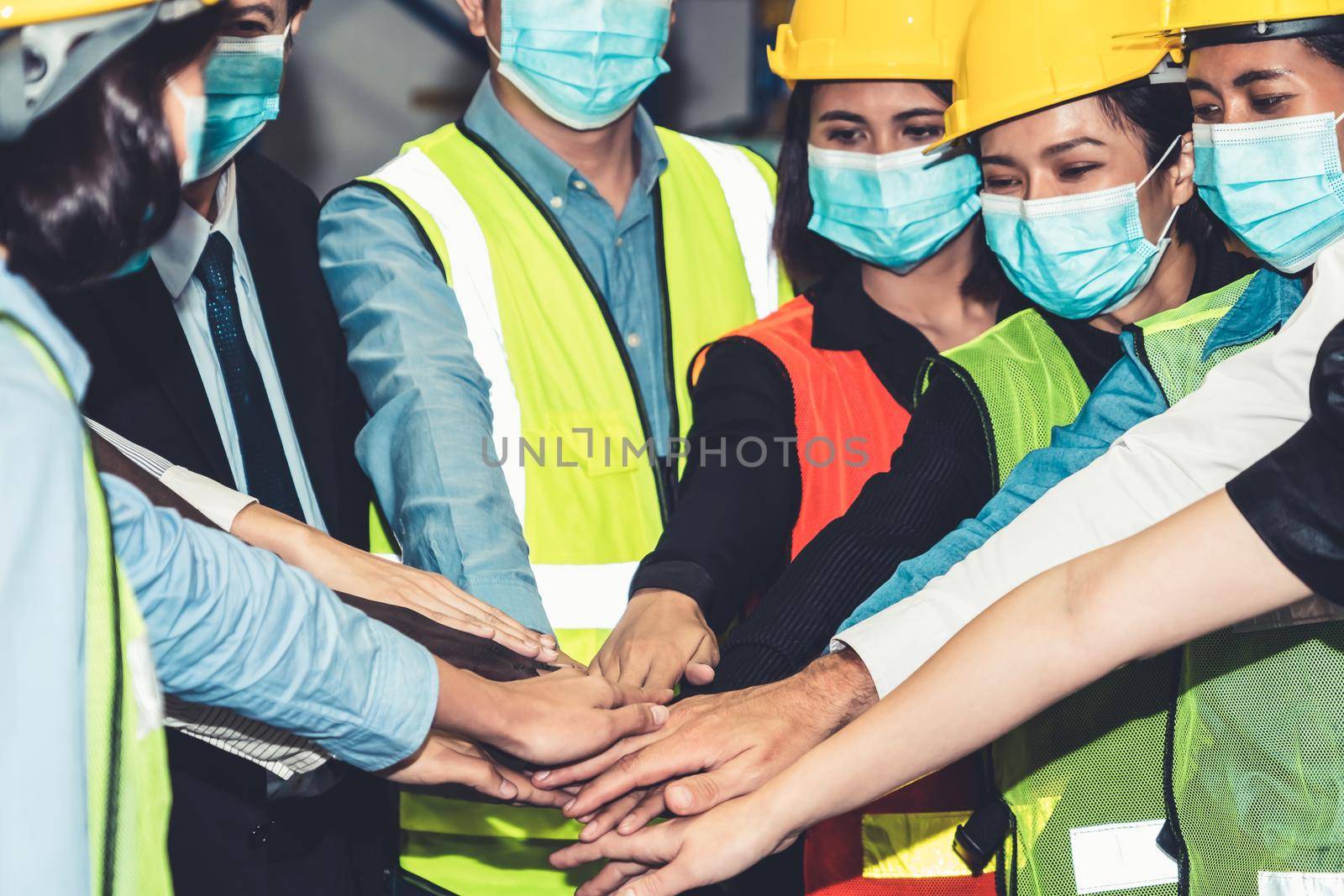 Group of factory industry worker working with face mask to prevent Covid-19 Coronavirus spreading during job reopening period .