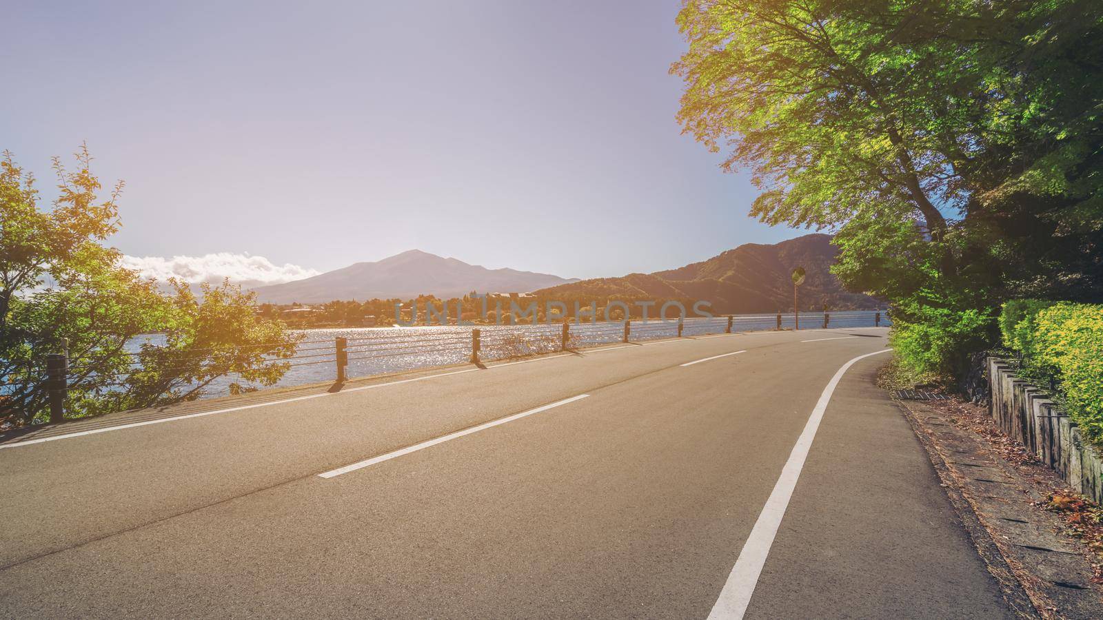 Beautiful road scenery with lake and mountain landscape background. Concept of travel, transportation, road trip and freedom.