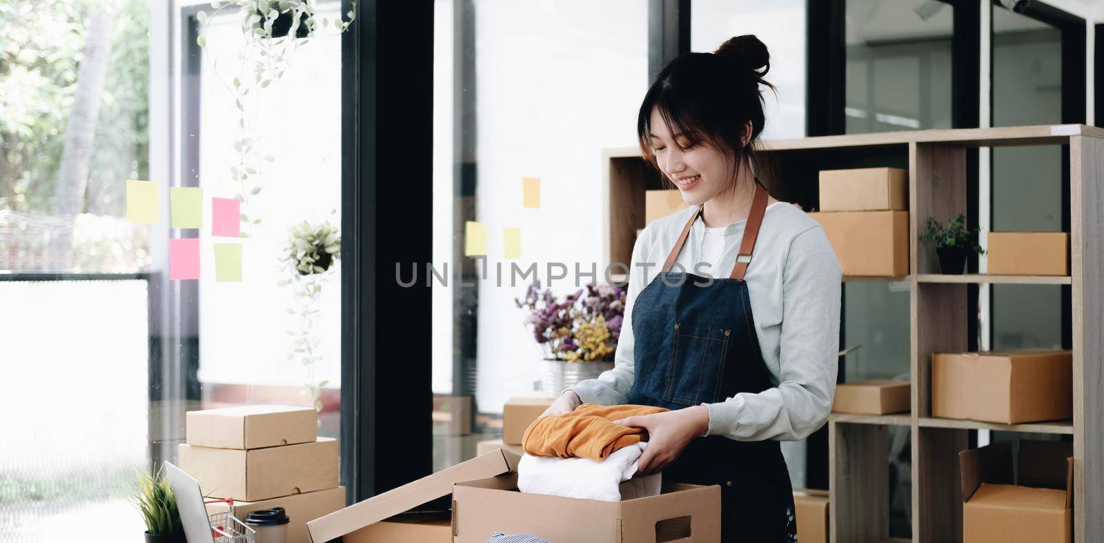 young start up small business owner packing cardboard box at workplace. freelance woman seller prepare parcel box of product for deliver to customer. Online selling, e-commerce, shipping concept by wichayada