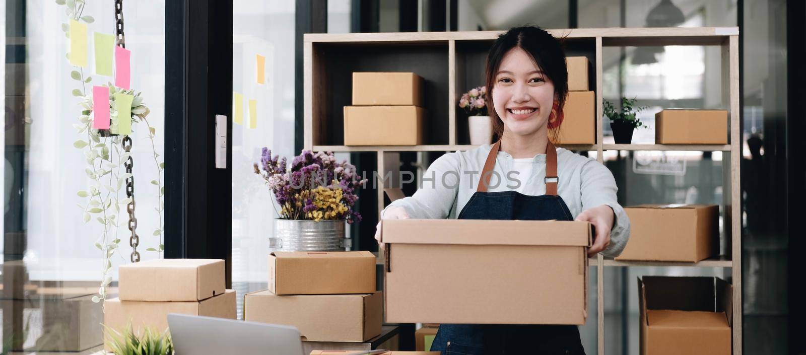 Small business owner concept, Portrait young attractive asian female owner startup business work happy with box at home prepare parcel delivery in sme supply chain..