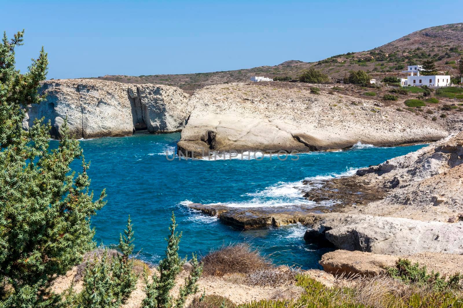 Milos island sea view with rocks, waves and small white houses