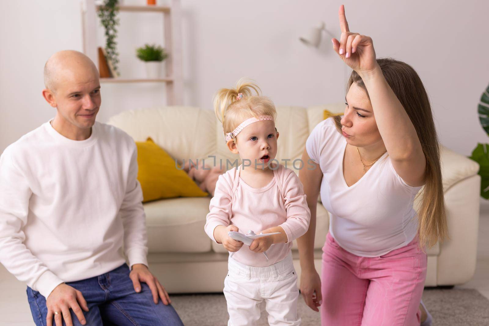 Cochlear implant on the child girl head and playing with mother and father. Hearing aid and deafness and innovative health technology concept by Satura86