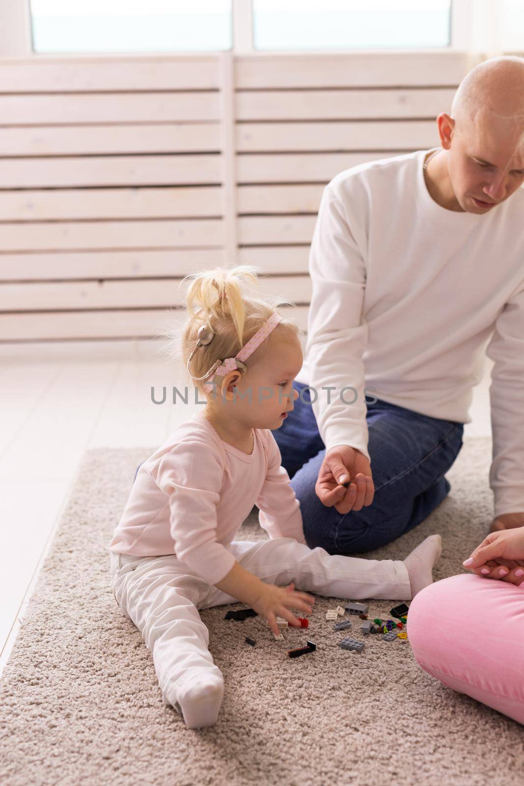 Baby with cochlear implants playing with her mother and father at home.
