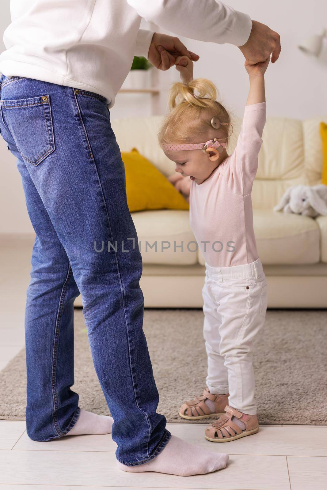 Baby with cochlear implants playing with her mother and father at home.