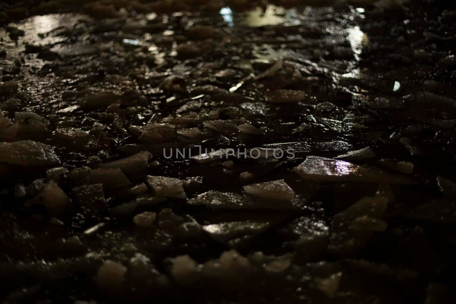 Texture of ice in dark. Broken ice. Puddle at night. View of surface of frozen water.