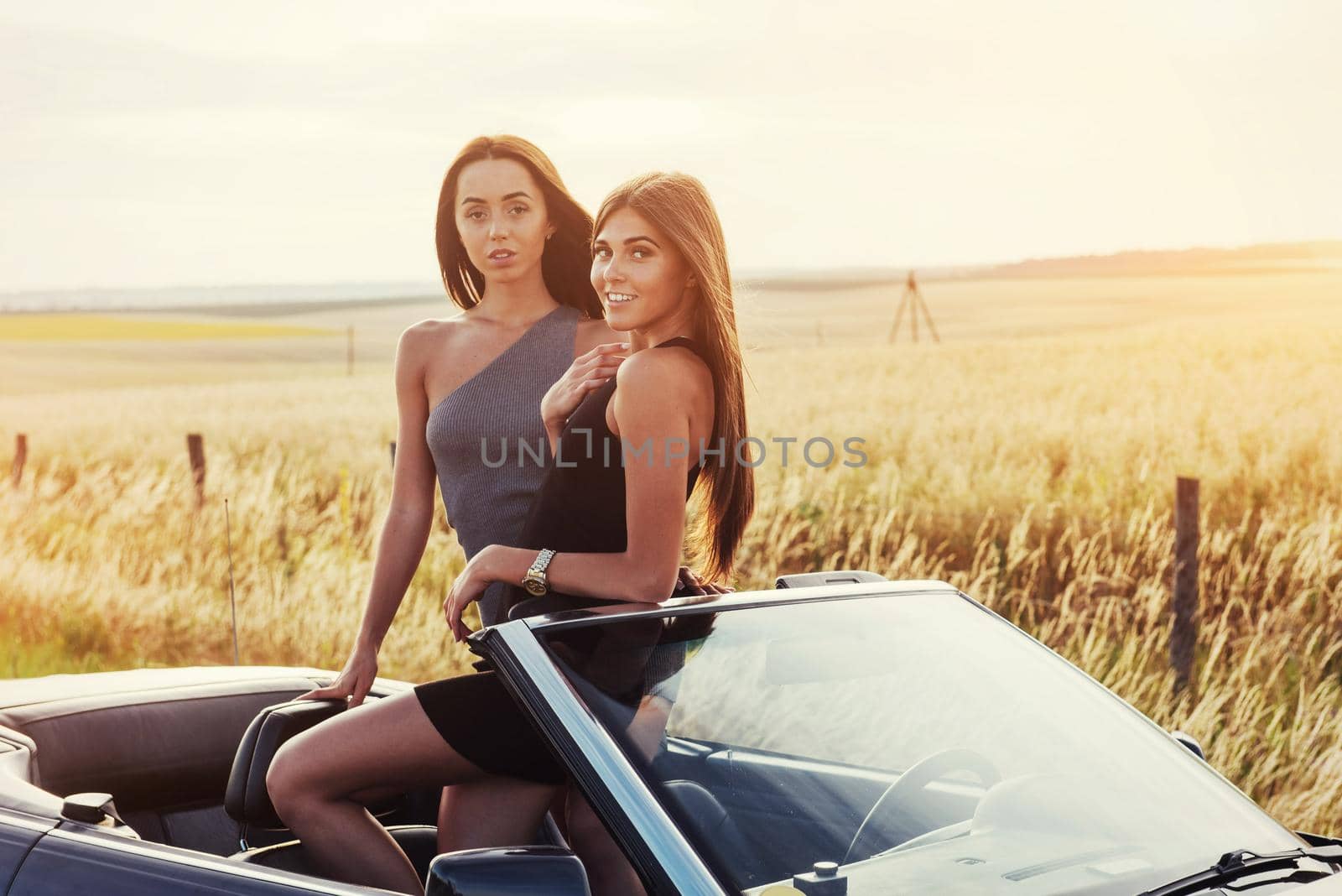 Girls posing for the camera in a black convertible.