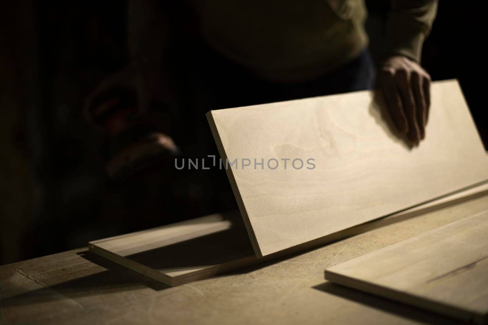 Carpenter holds tree. Worker chooses board. Details of carpentry workshop. by OlegKopyov