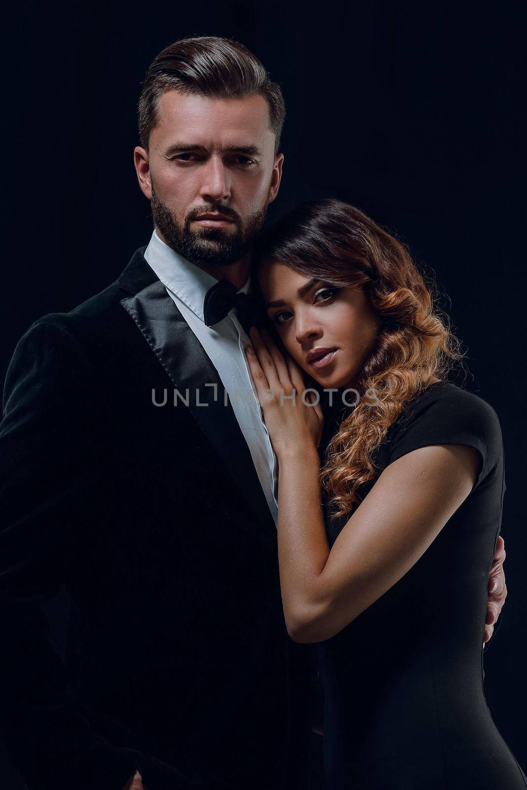 Portrait of young couple in love posing at studio dressed in classic clothes