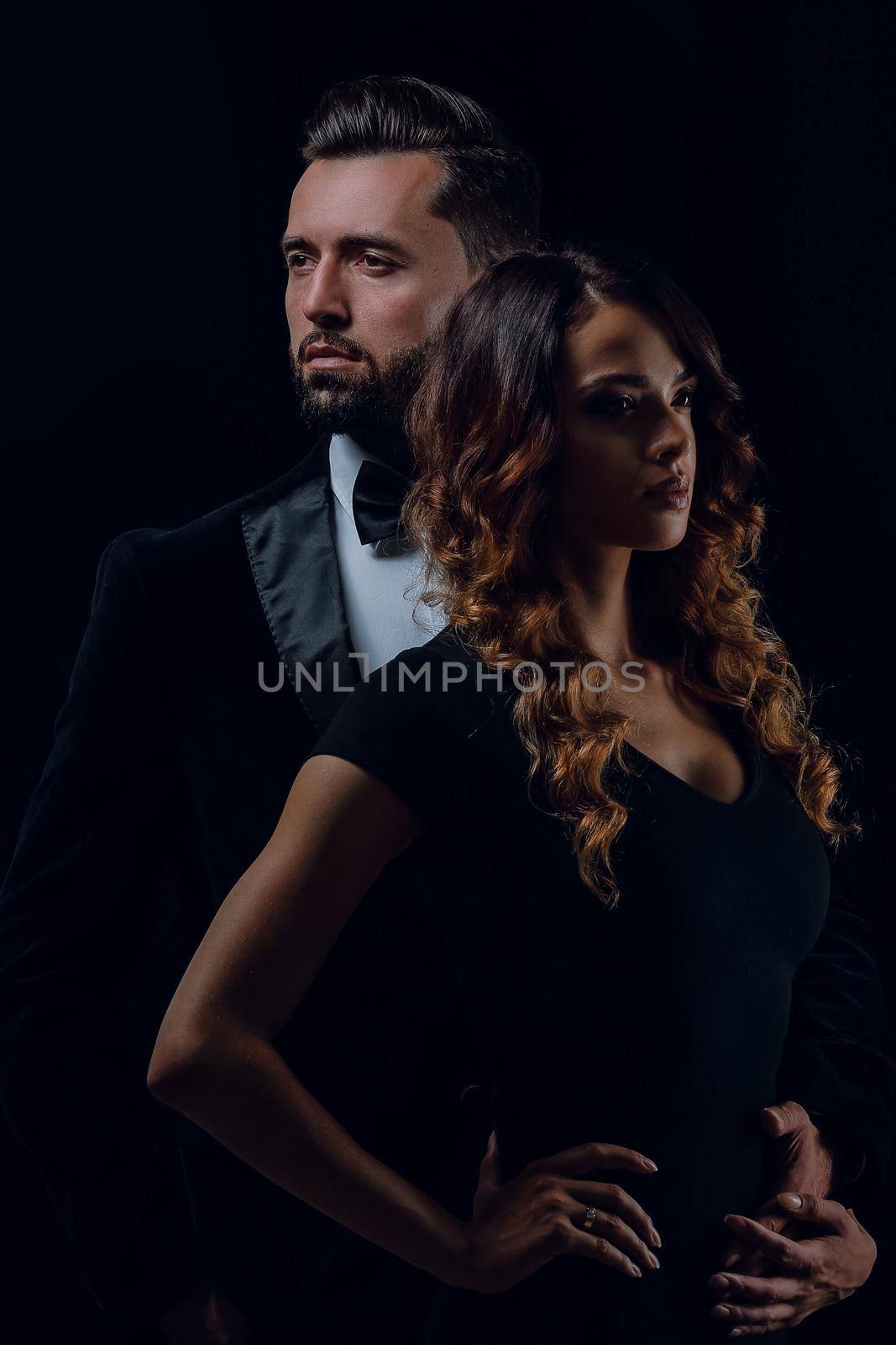 Portrait of a beautiful young couple in love posing at studio over dark background.