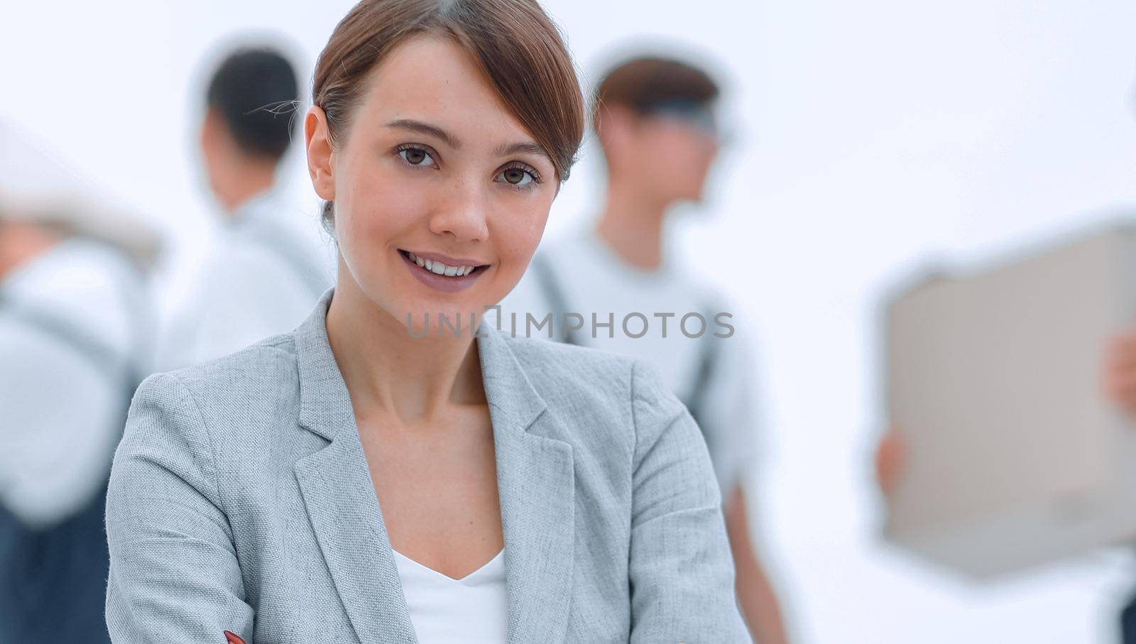 Smiling manager holding clipboard on blurred background with movers and boxes.