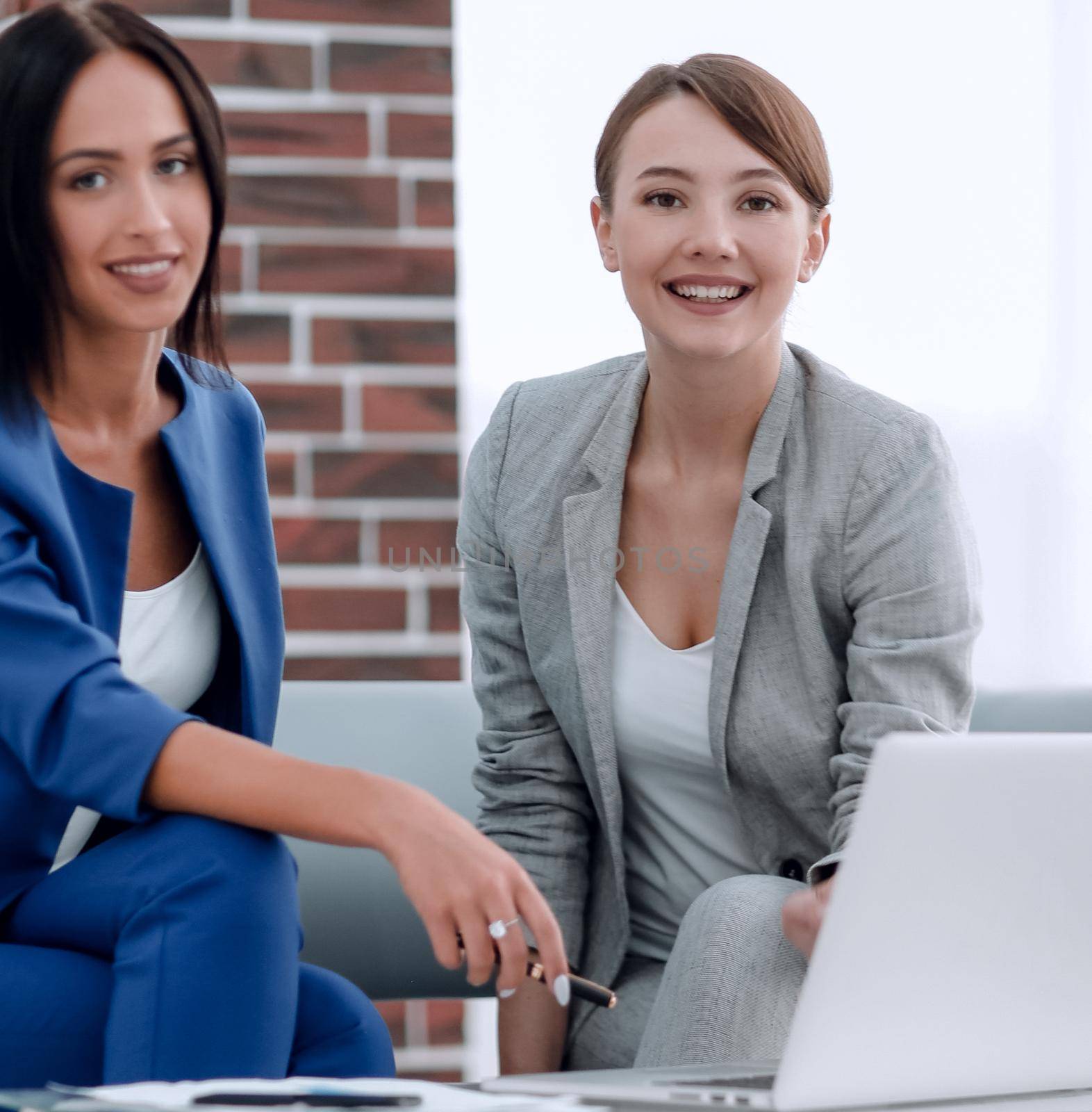 Smiling businesswomen discussing over tablet PC in office