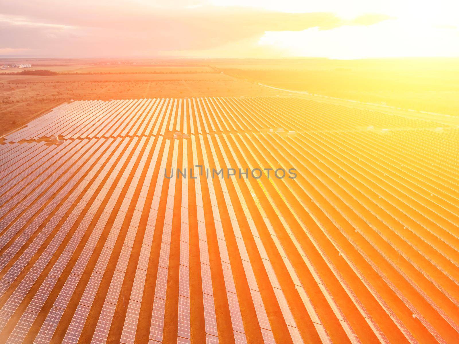 Aerial top view of a solar panels power plant. Photovoltaic solar panels at sunrise and sunset in countryside from above. Modern technology, climate care, earth saving, renewable energy concept