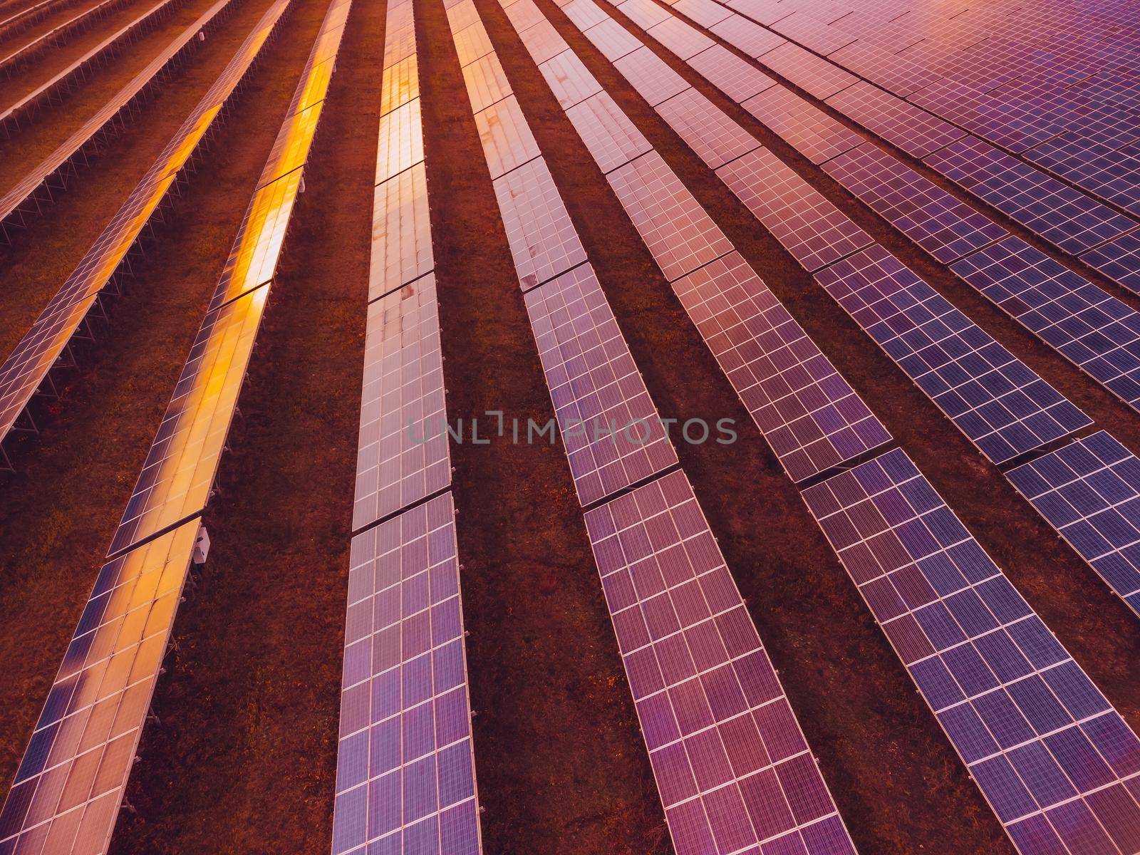 Aerial top view of a solar panels power plant. Photovoltaic solar panels at sunrise and sunset in countryside from above. Modern technology, climate care, earth saving, renewable energy concept