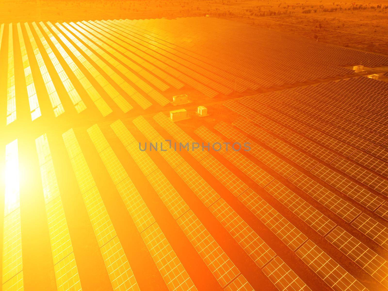 Aerial top view of a solar panels power plant. Photovoltaic solar panels at sunrise and sunset in countryside from above. Modern technology, climate care, earth saving, renewable energy concept