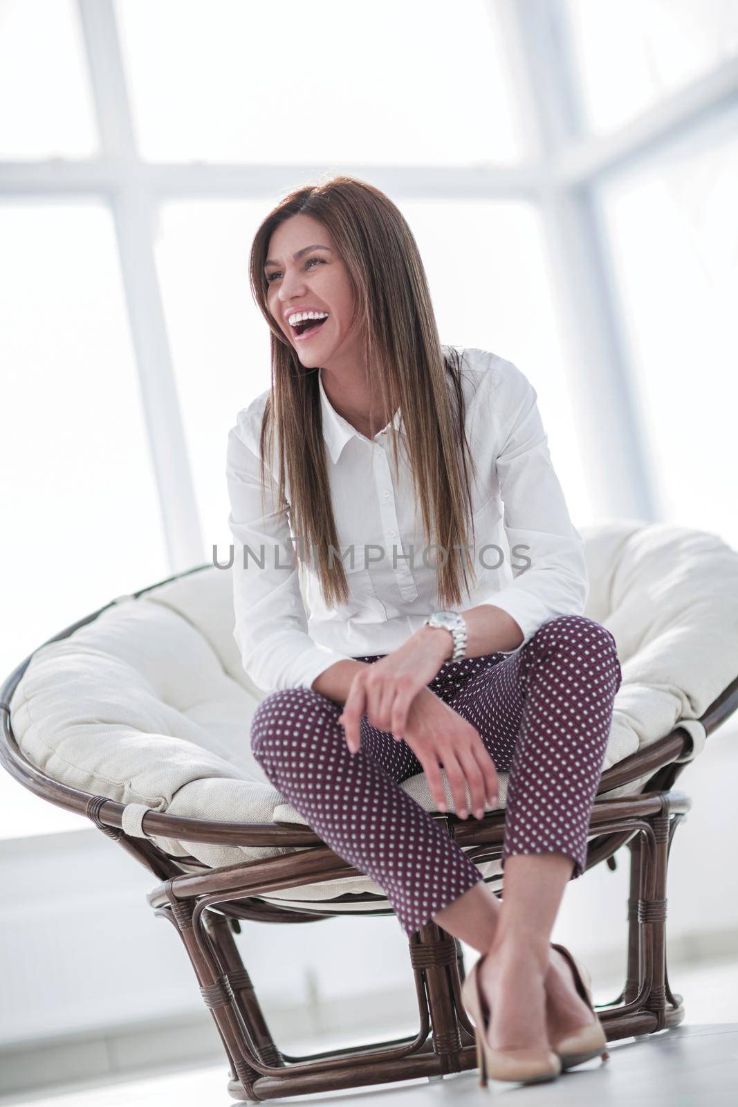 laughing young woman sitting in comfortable chair by asdf