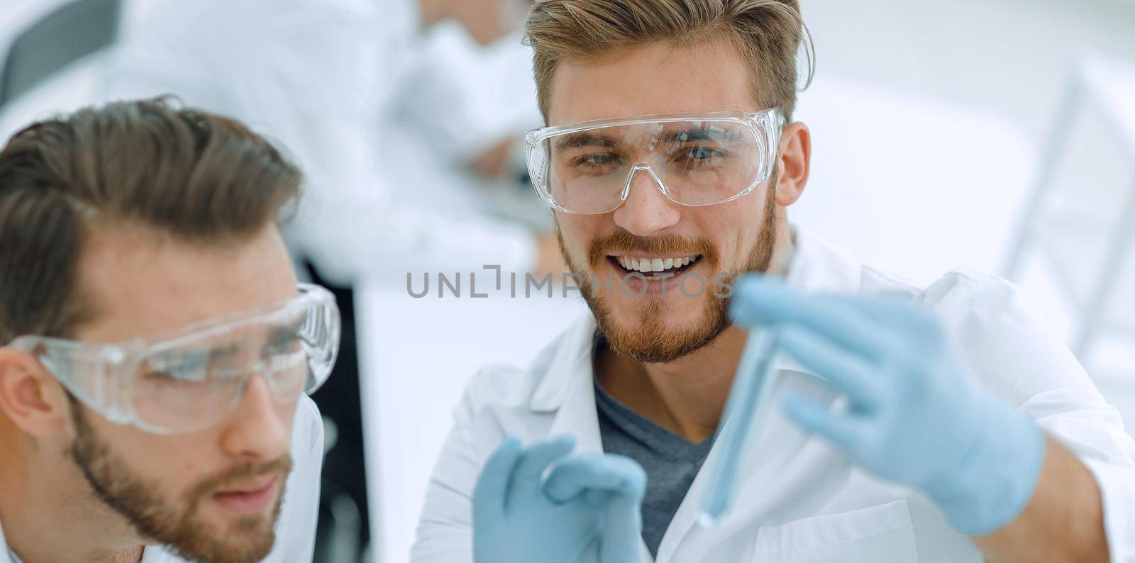 two biologist examining liquid in a test tube by asdf