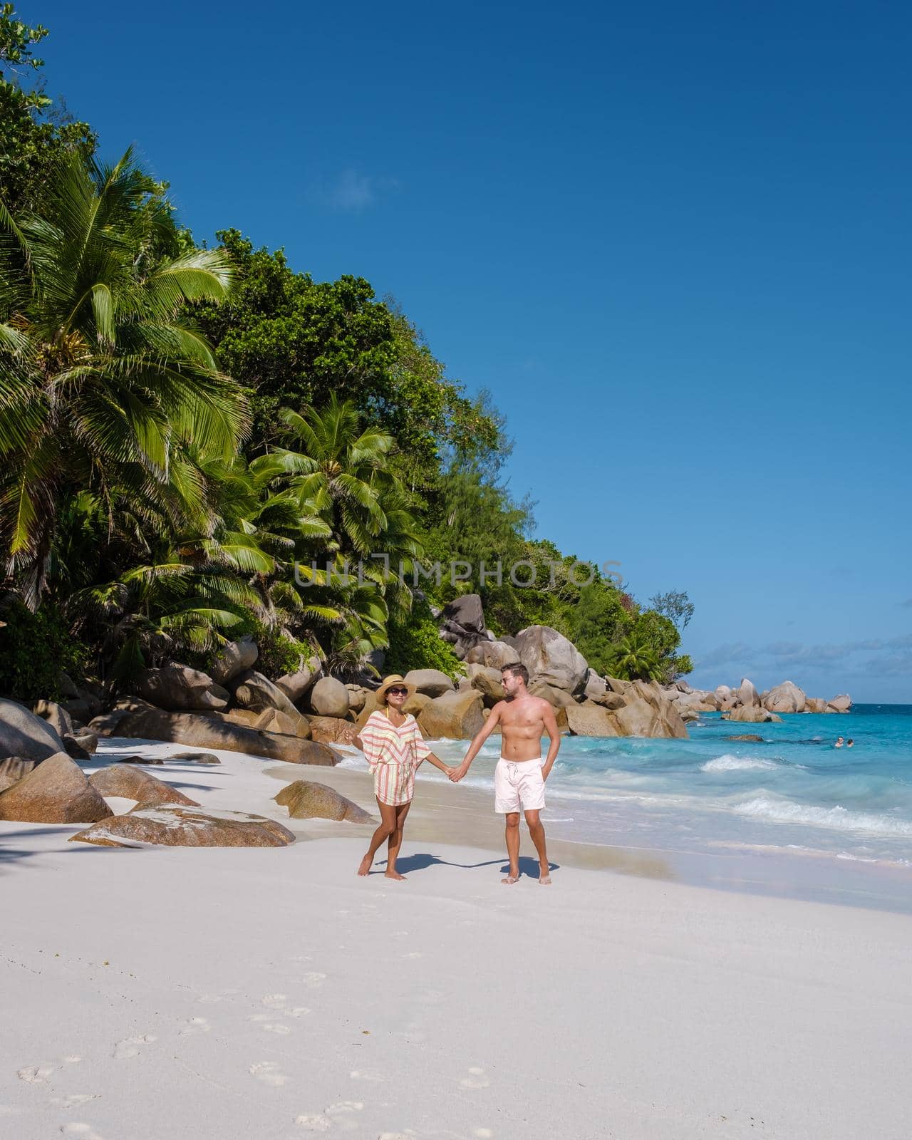 Anse Georgette Praslin Seychelles, young couple of men and woman on a tropical beach during a luxury vacation in Seychelles. Tropical beach Anse Georgette Praslin Seychelles.