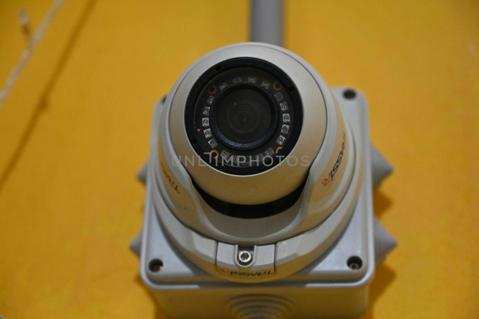 Photo of a surveillance video camera against a yellow wall