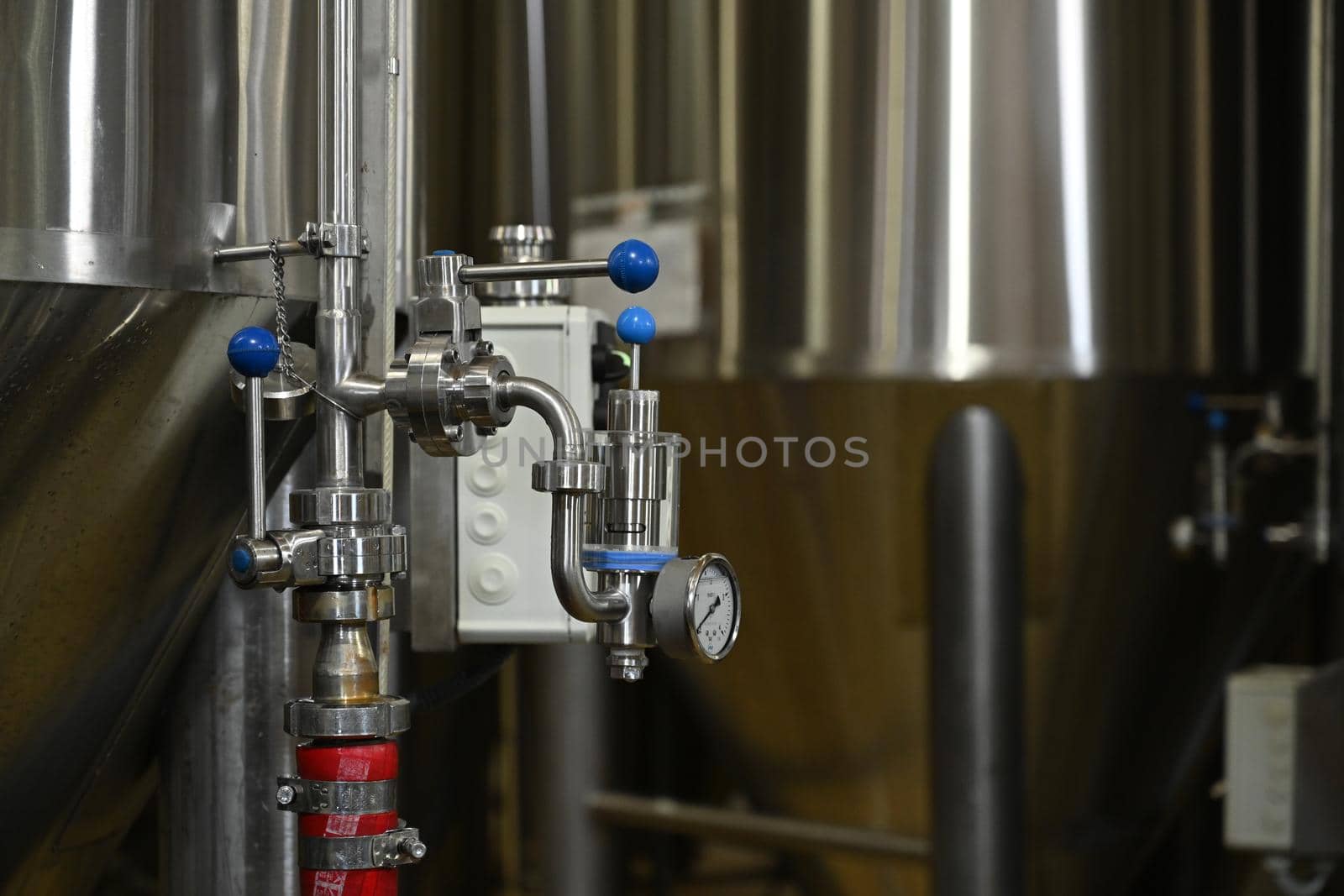 Taps in equipment with a manometer on a blurred background of a beer production