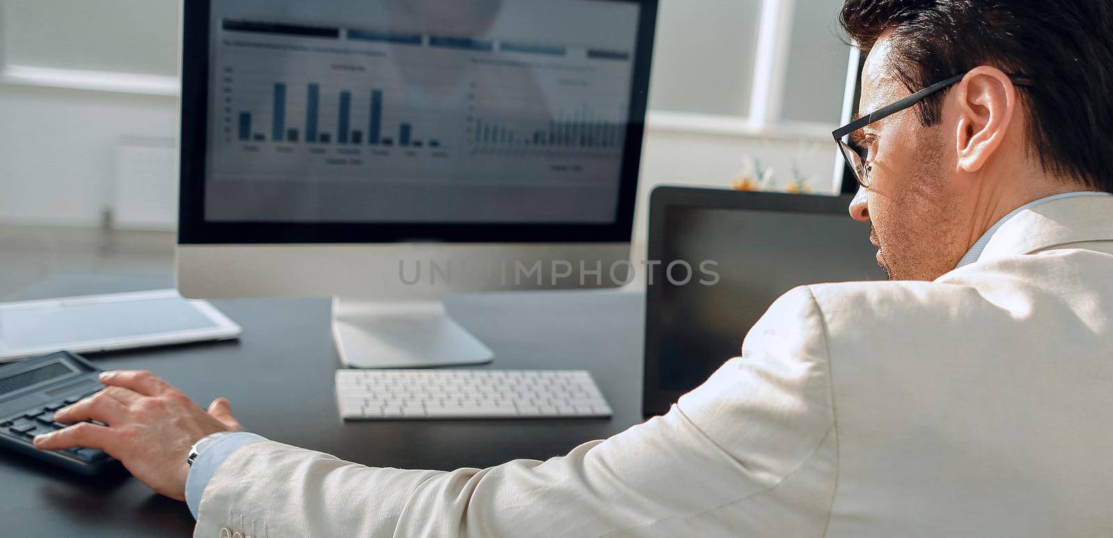 rear view. businessman analyzing graphs on computer at Desk in office