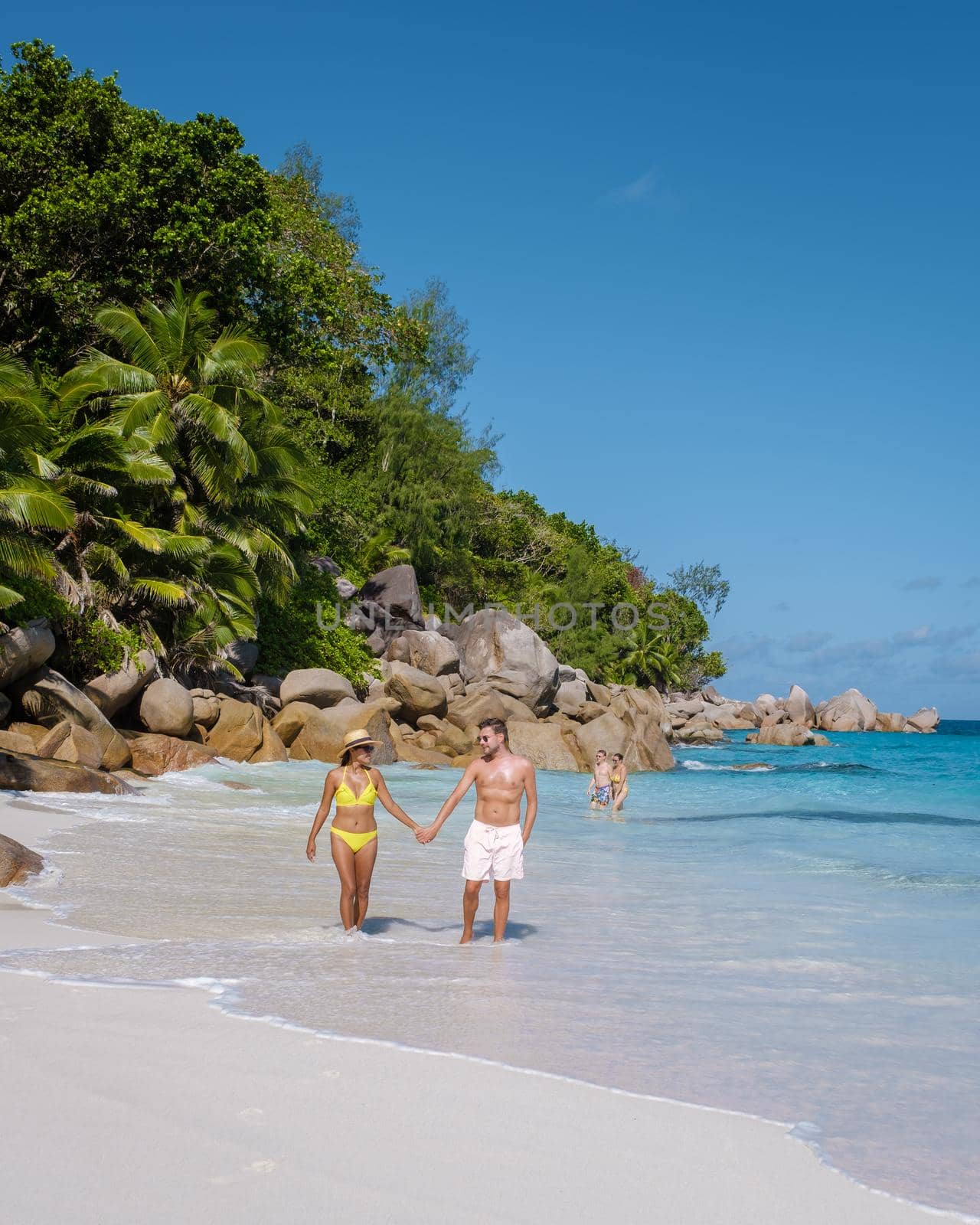 Anse Georgette Praslin Seychelles, young couple of men and woman on a tropical beach during a luxury vacation in Seychelles. Tropical beach Anse Georgette Praslin Seychelles.