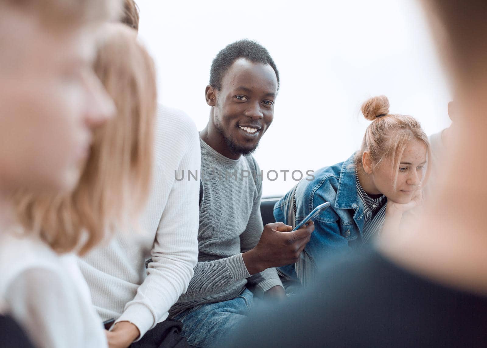 smiling guy sitting in a circle of her friends by asdf