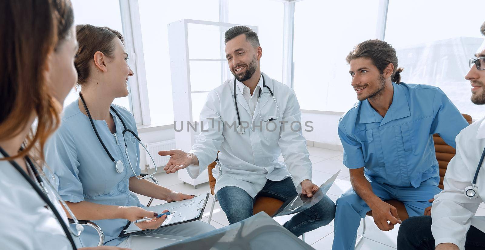 medical staff discussing x-ray of a patient sitting in the office