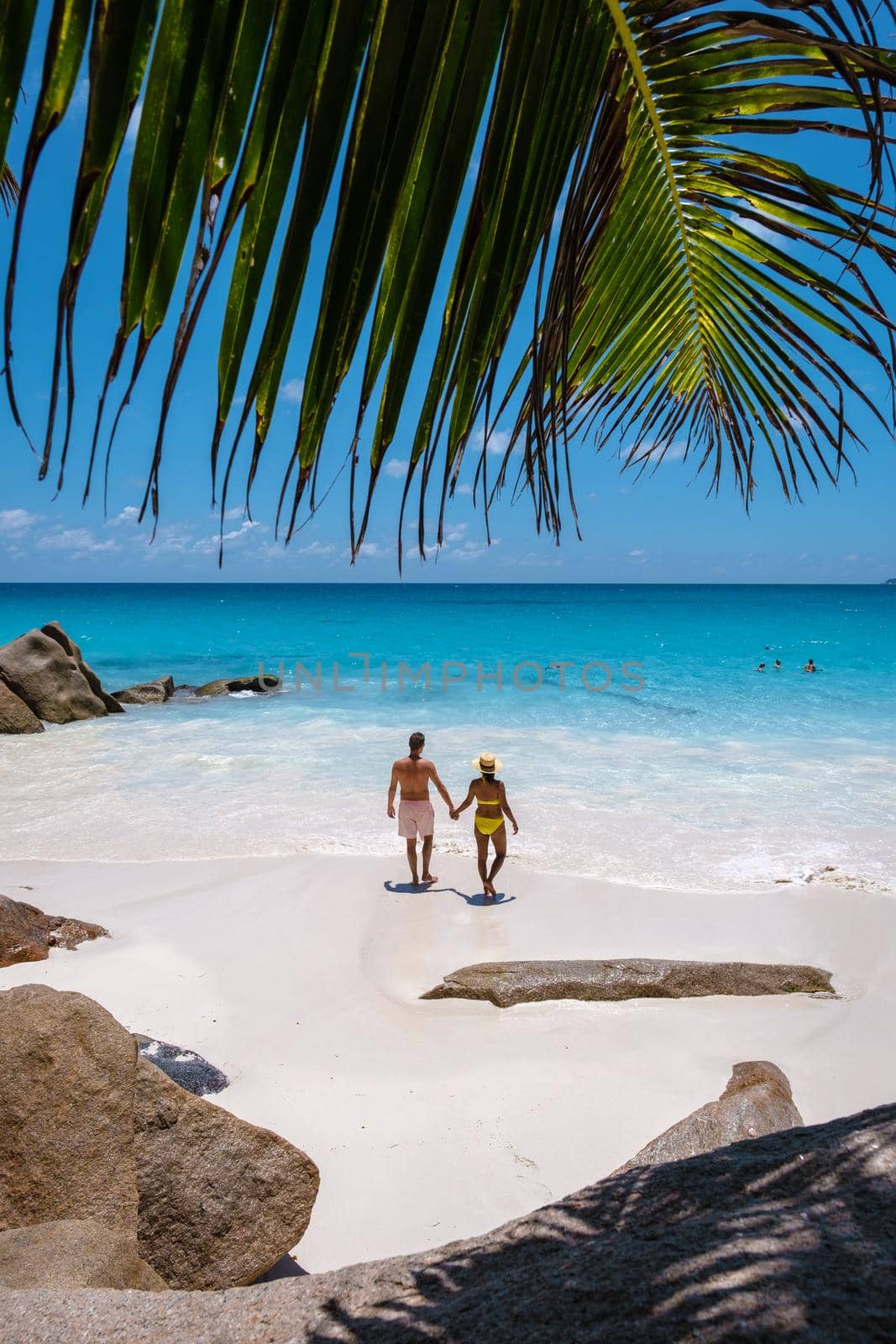 Anse Georgette Praslin Seychelles, young couple of men and woman on a tropical beach during a luxury vacation in Seychelles. Tropical beach Anse Georgette Praslin Seychelles.