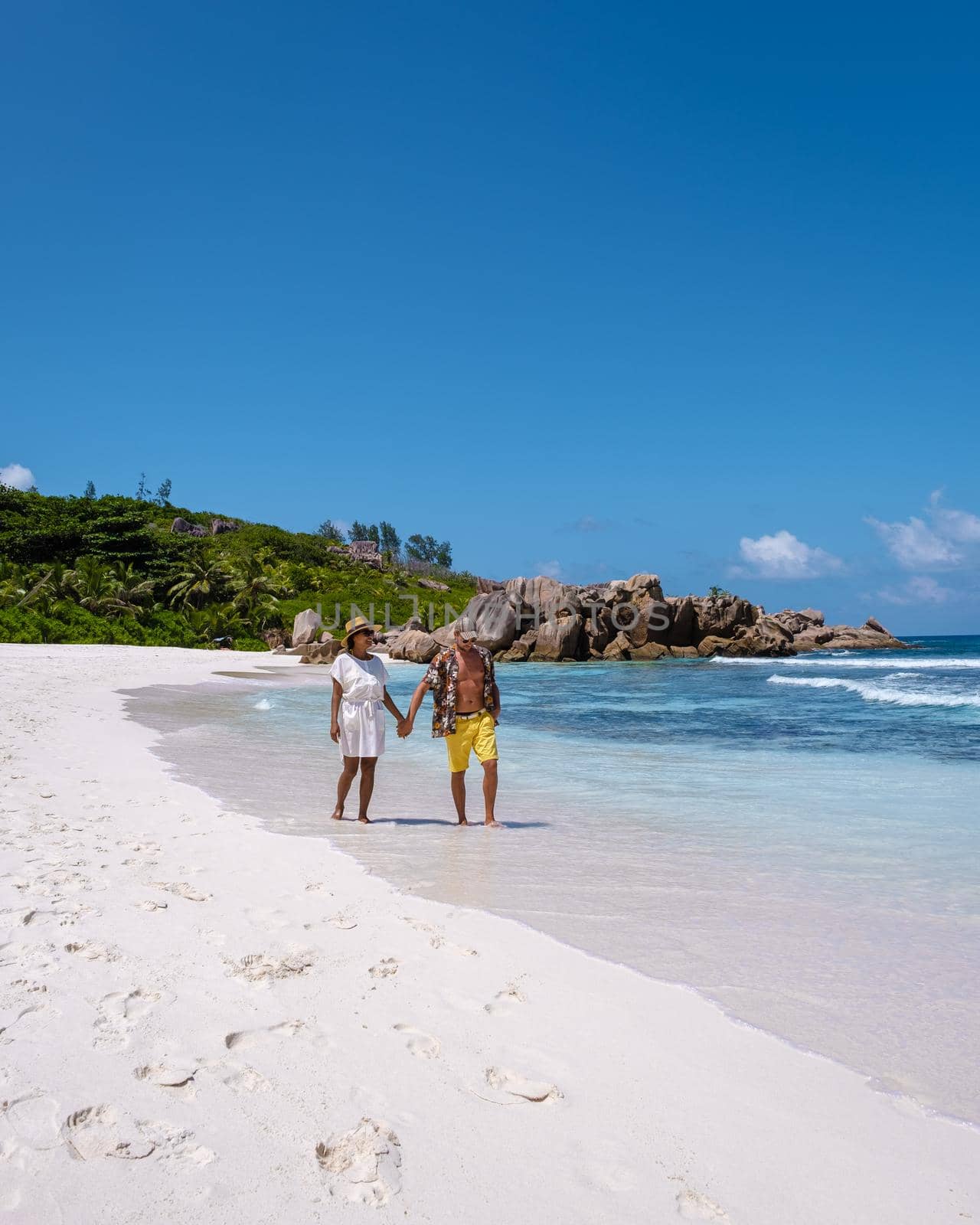 Anse Cocos La Digue Seychelles, a young couple of men and women on a tropical beach during a luxury vacation in Seychelles. Tropical beach Anse Cocos La Digue Seychelles.