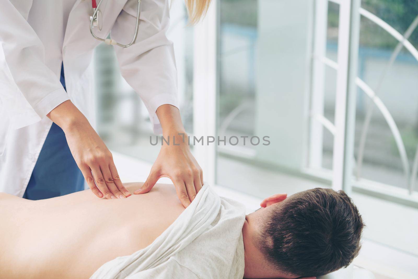 Woman doctor is examining male patient in hospital office. Healthcare and medical service.