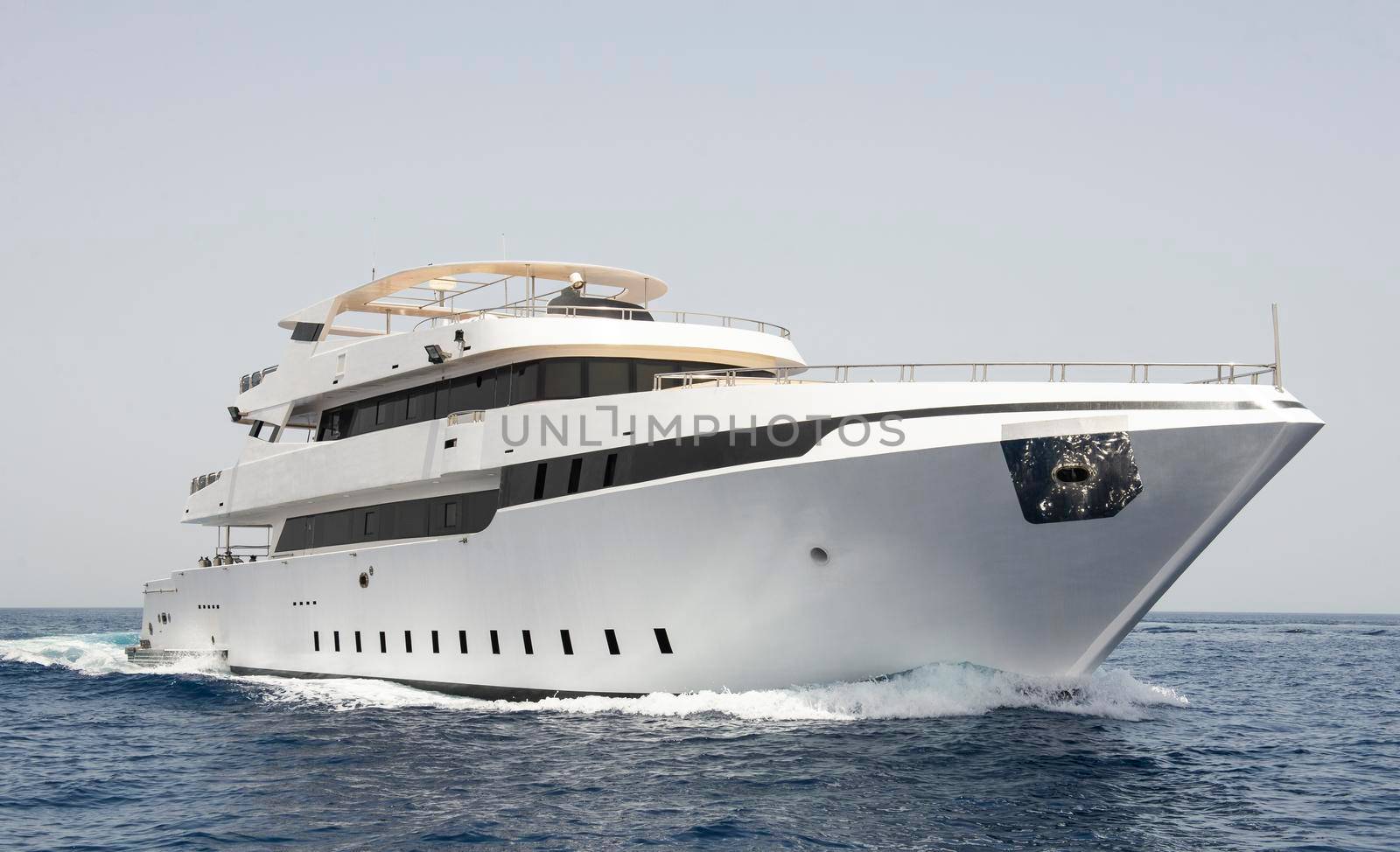 A large luxury private motor yacht under way sailing on tropical sea with bow wave