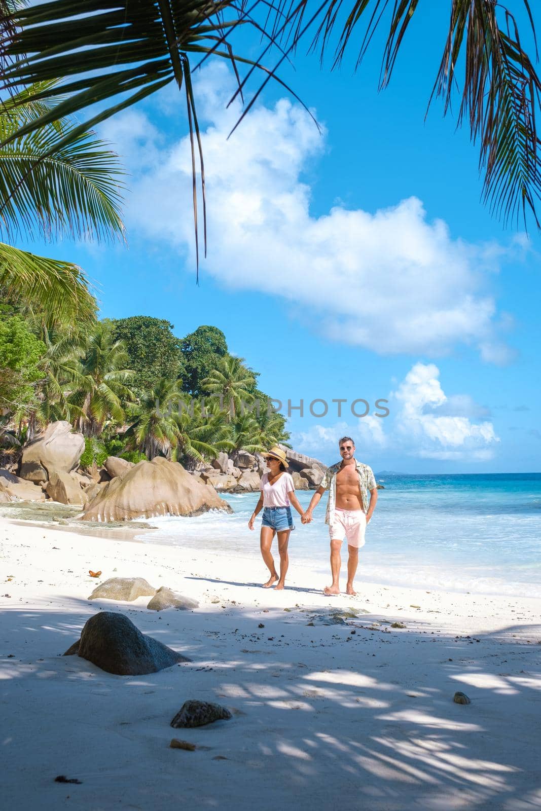 Anse Patates, La Digue Seychelles, a young couple of men and women on a tropical beach during a luxury vacation in Seychelles. Tropical beach Anse Patates, La Digue Seychelles