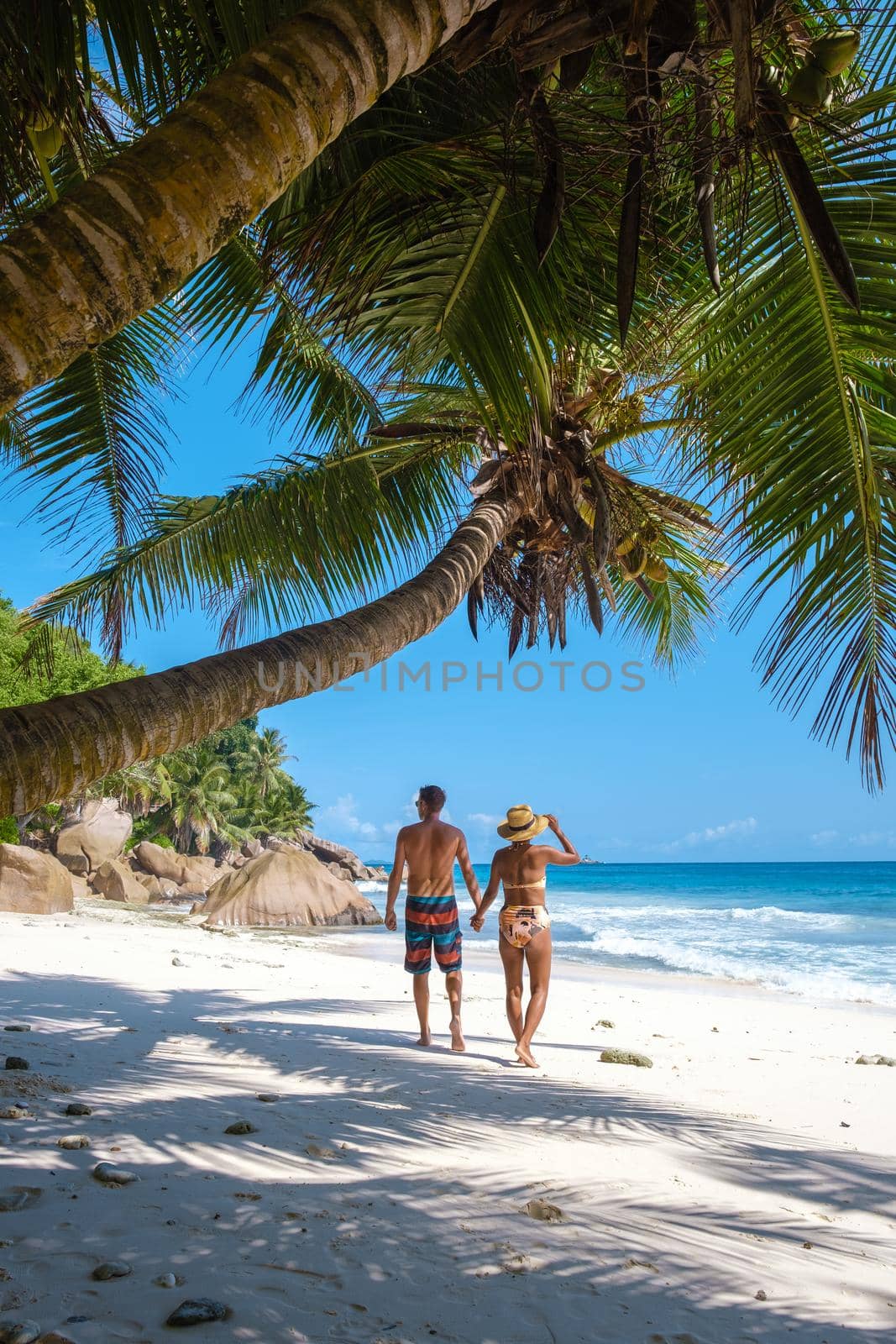 Anse Patates, La Digue Seychelles, a young couple of men and women on a tropical beach during a luxury vacation in Seychelles. Tropical beach Anse Patates, La Digue Seychelles