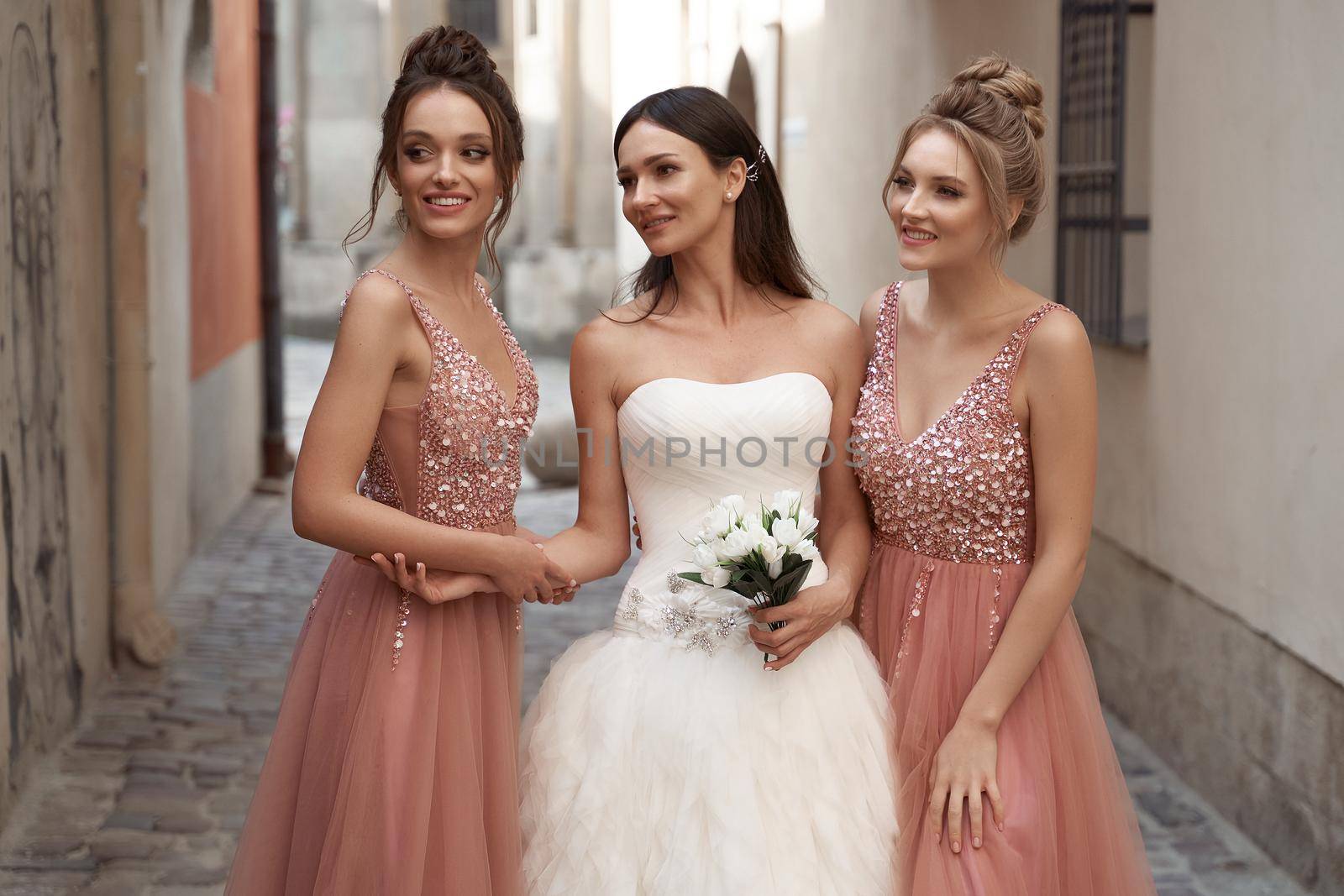 Beautiful bride and bridesmaids. Wedding day in old beautiful European city. by berezko