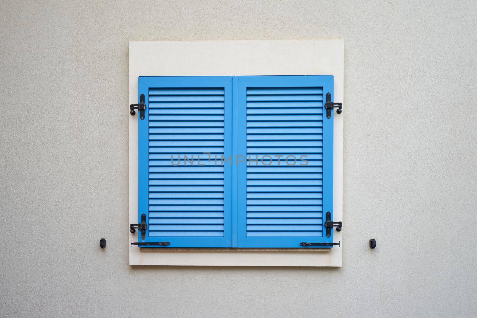Blue plastic window shutters on a wall of residential building.
