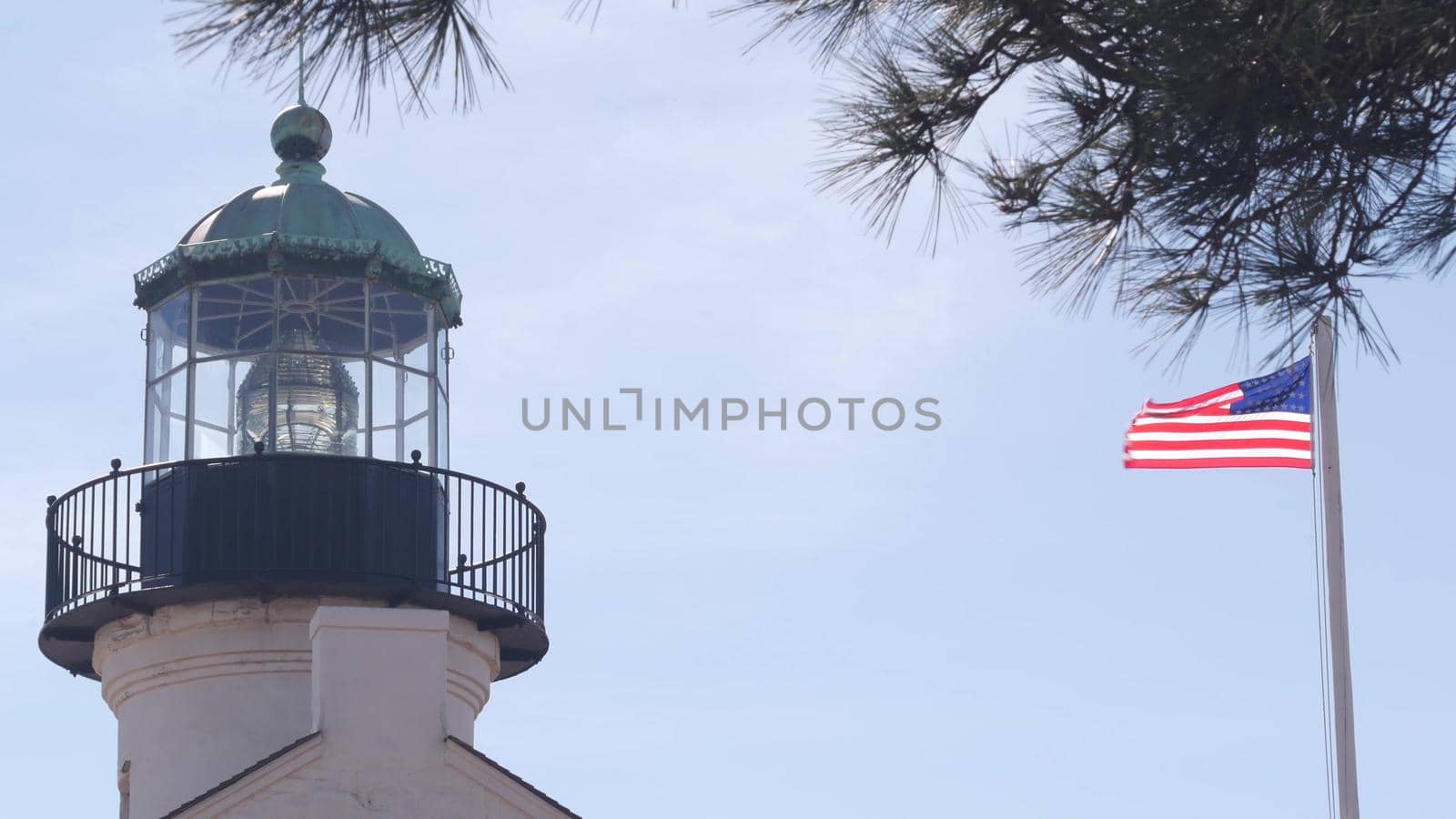 Vintage lighthouse tower, retro light house, old historic classic beacon with fresnel lens, american flag. Nautical navigation, 1855. Point Loma, San Diego, California USA. Seamless looped cinemagraph